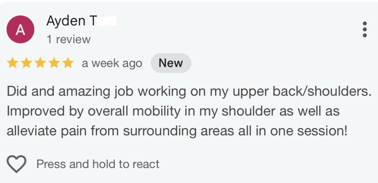 A modern building with a wooden exterior and large glass window, set against a mountainous landscape with dry grass and sparse trees.