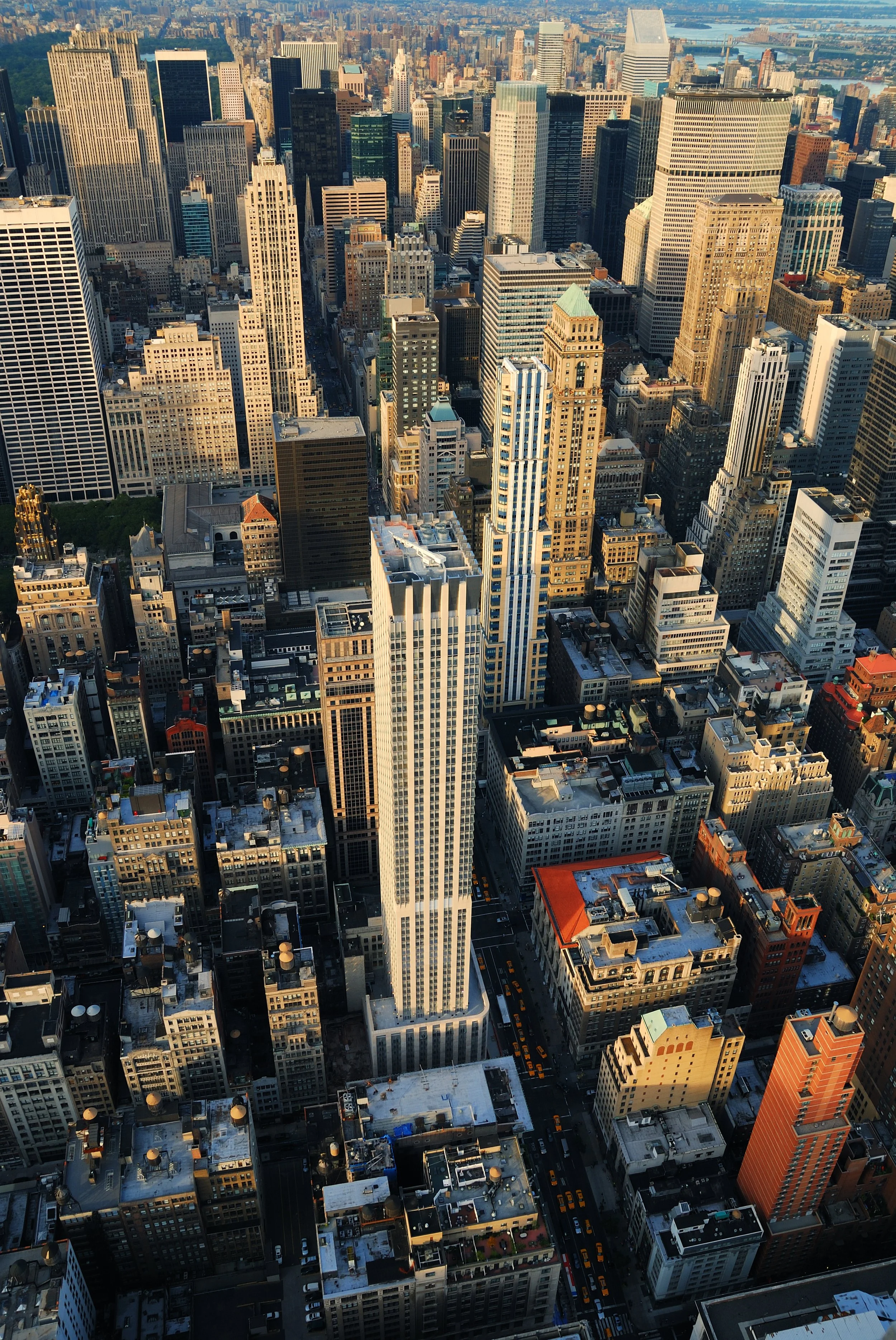Aerial view of Manhattan, New York City, showcasing tall skyscrapers and densely packed buildings with streets and taxis running through the city.