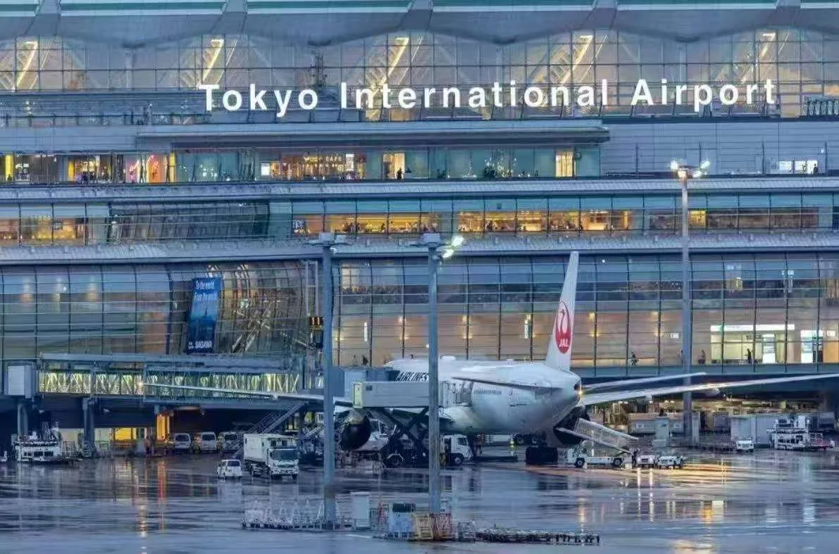 Exterior of Tokyo International Airport with an airplane parked at the gate.