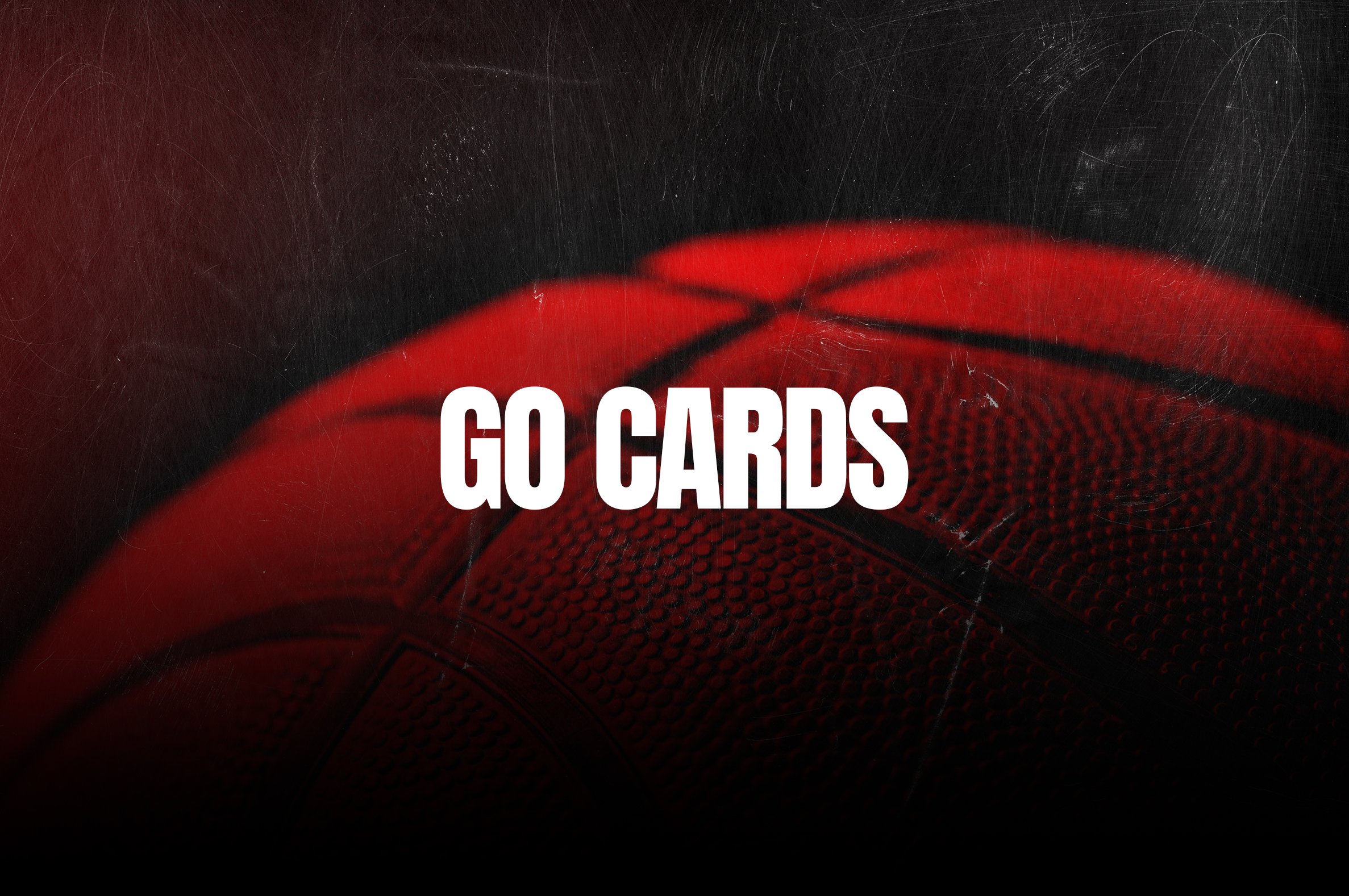 Close-up of a red basketball with white bold text saying 'GO CARDS' over it.