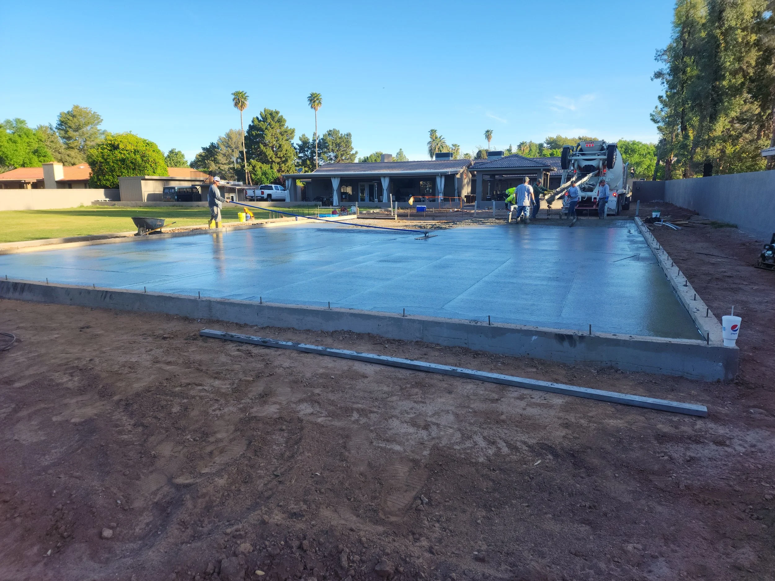 Construction workers pouring a concrete slab as the foundation for a custom garage.