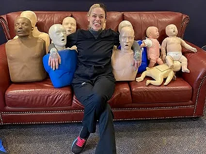 Person sitting on a red leather couch surrounded by multiple mannequin heads and body parts.