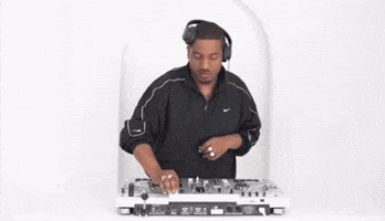 A DJ wearing headphones and a black Nike jacket operating a DJ controller. OFFICE1102-MASTER-COPY-RASHAAD-DENZEL