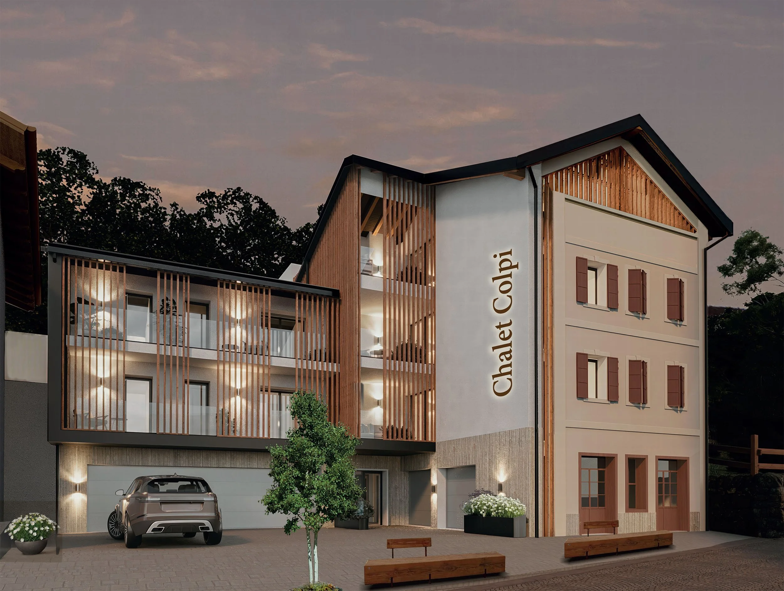 Edificio moderno con tre piani, loggias con luci calde, facciata in bianco e legno, con il nome 'Chalet Calpi' scritto verticalmente, parcheggio con auto, panchine, piante e luci esterne, al tramonto.