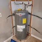 A water heater in a utility closet with copper pipes connected on top and bottom.