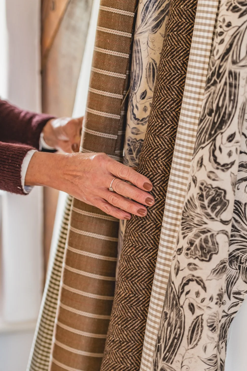 Person shopping for fabric, holding various patterned fabric swatches.