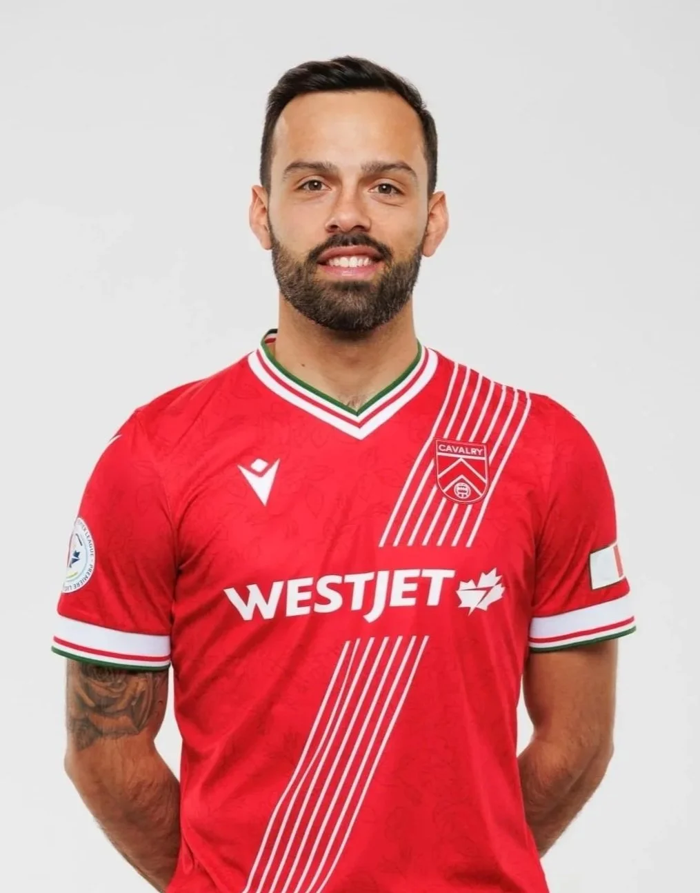 A man in a red soccer jersey standing against a white background.