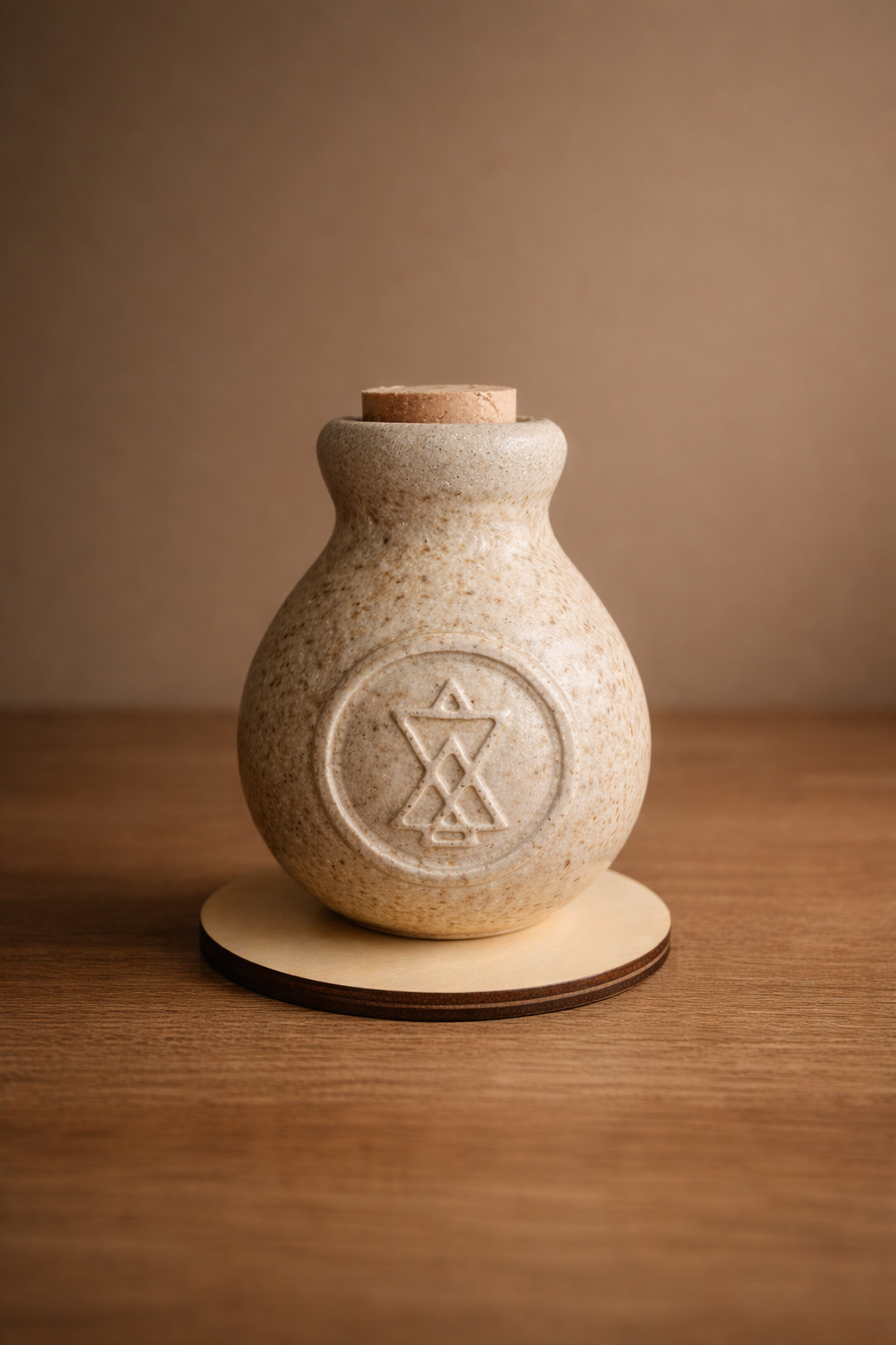 Une petite jarre en céramique beige avec un motif en forme d'étoile et de symboles à l'intérieur, posée sur une surface en bois.