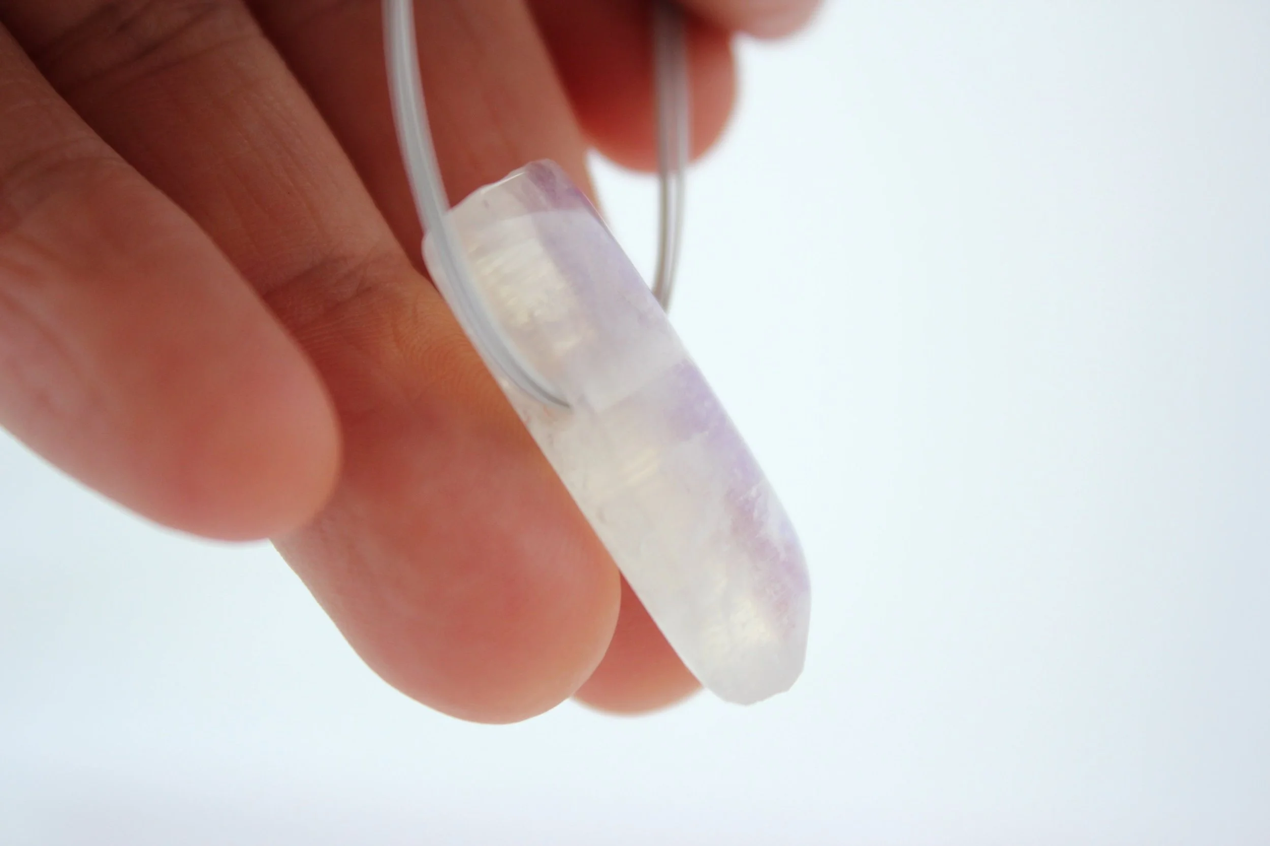 Main tenant une prothèse auditive translucide.