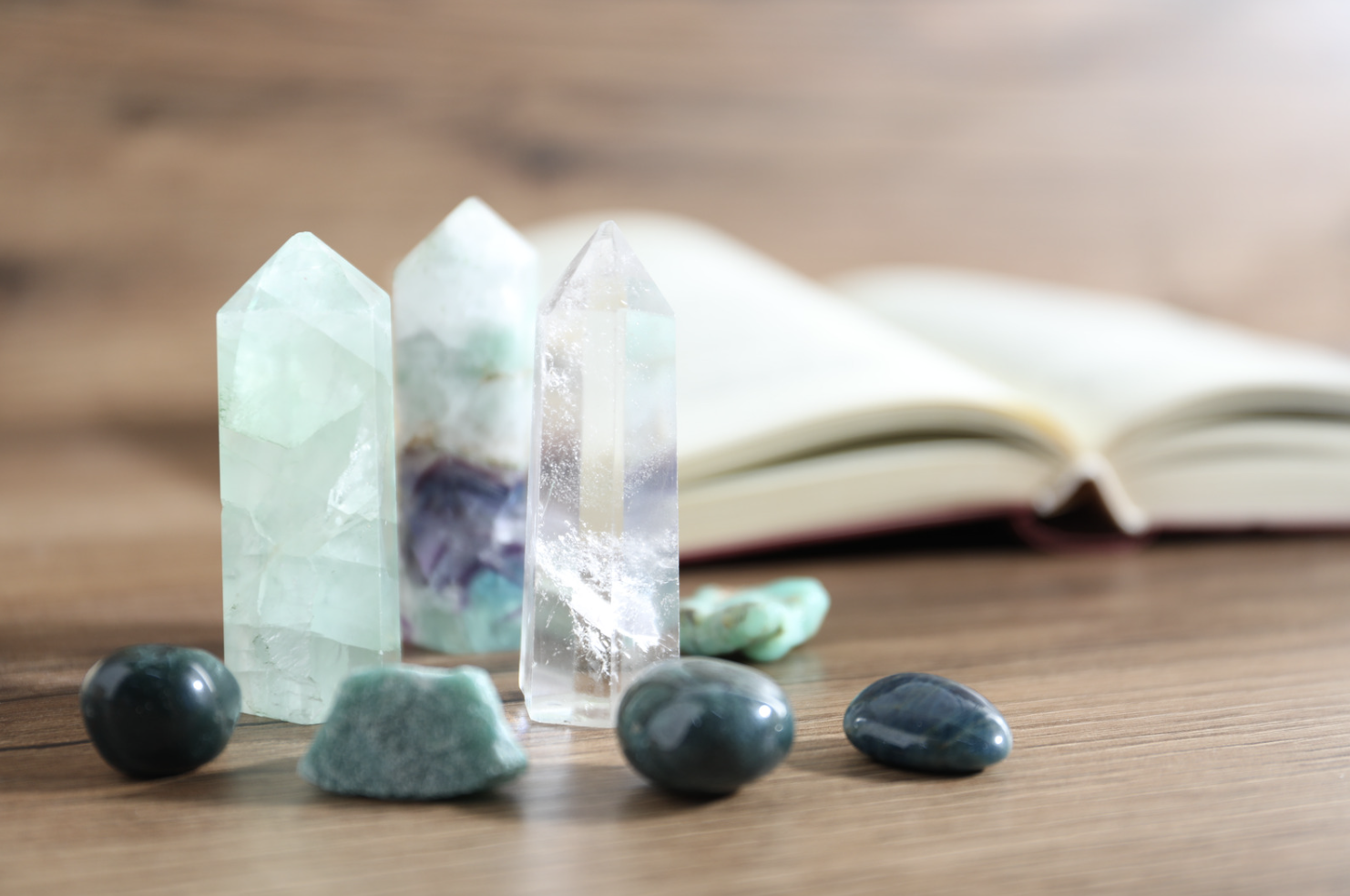 Pierres précieuses et cristaux sur une surface en bois avec un livre ouvert en arrière-plan