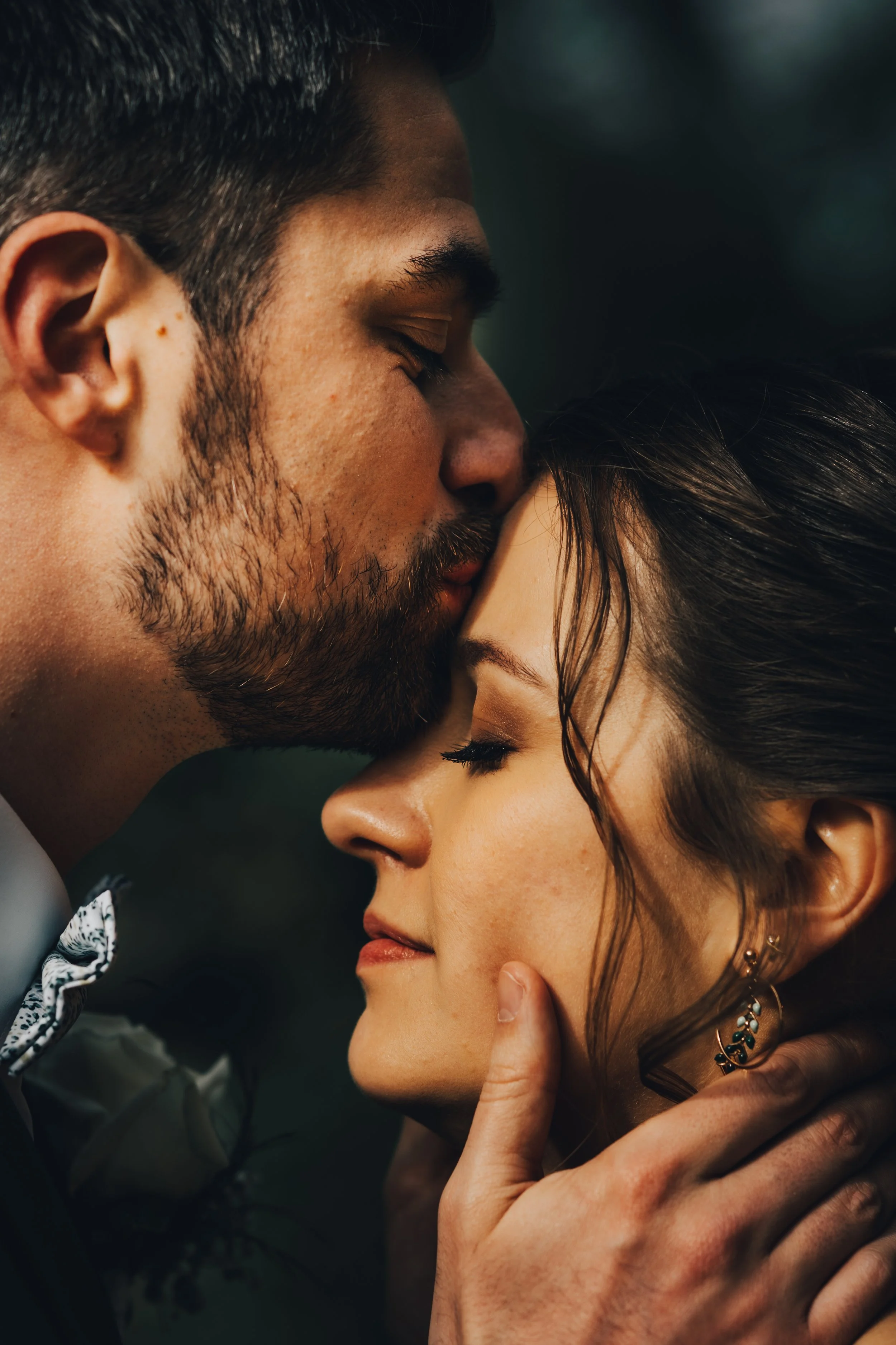 Un homme et une femme se tiennent très proches, le visage de l'homme proche de celui de la femme, semblant partager un moment intime.