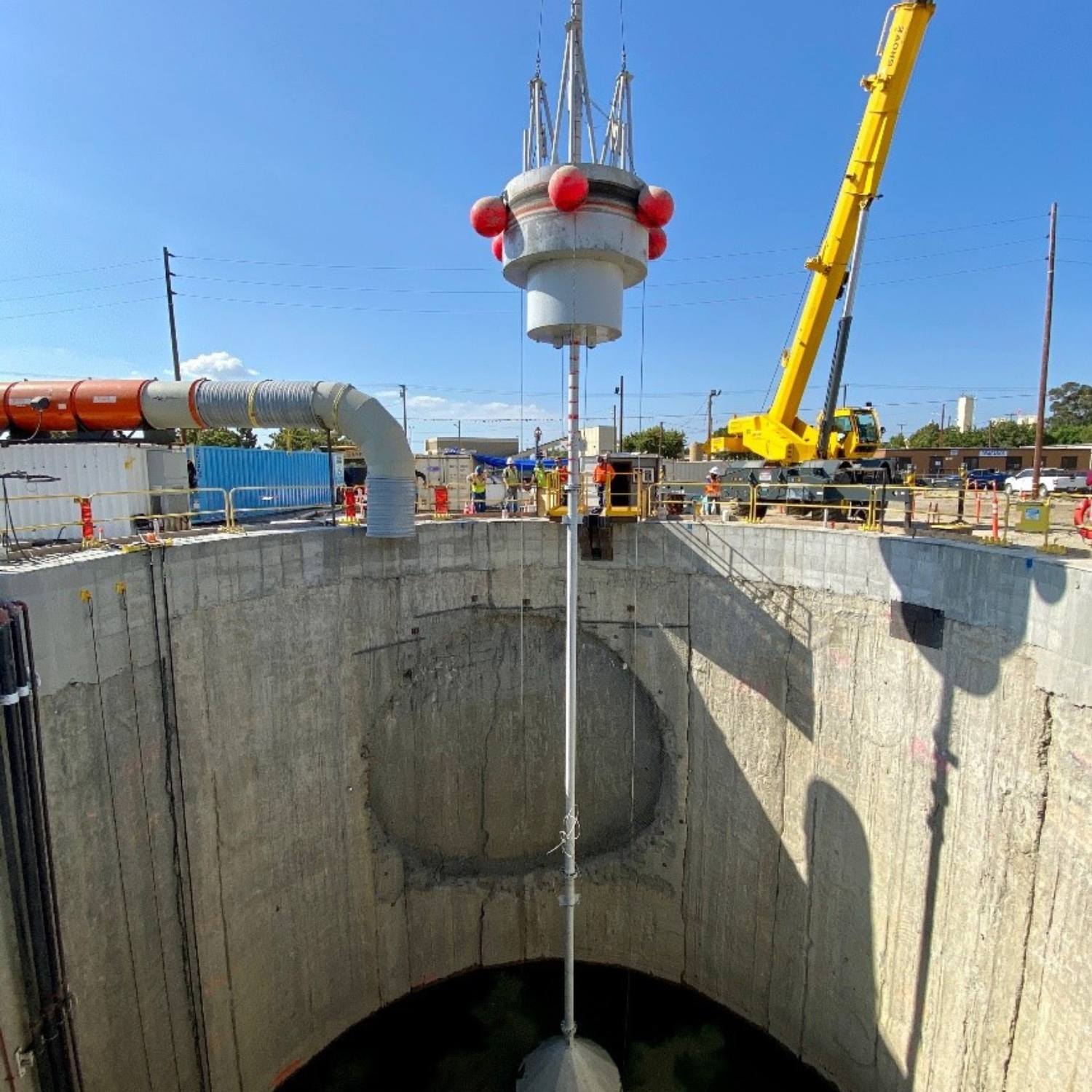 View of a tremie (long hollow tube) pouring concrete at the bottom of a shaft below the water table to create the floor slab.