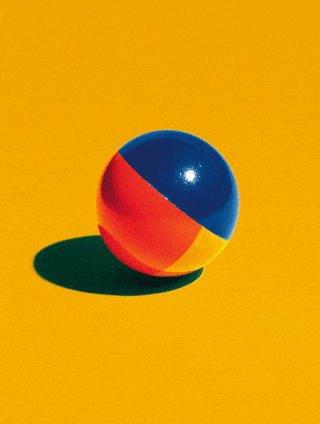 Colorful beach ball on a yellow background with shadow.