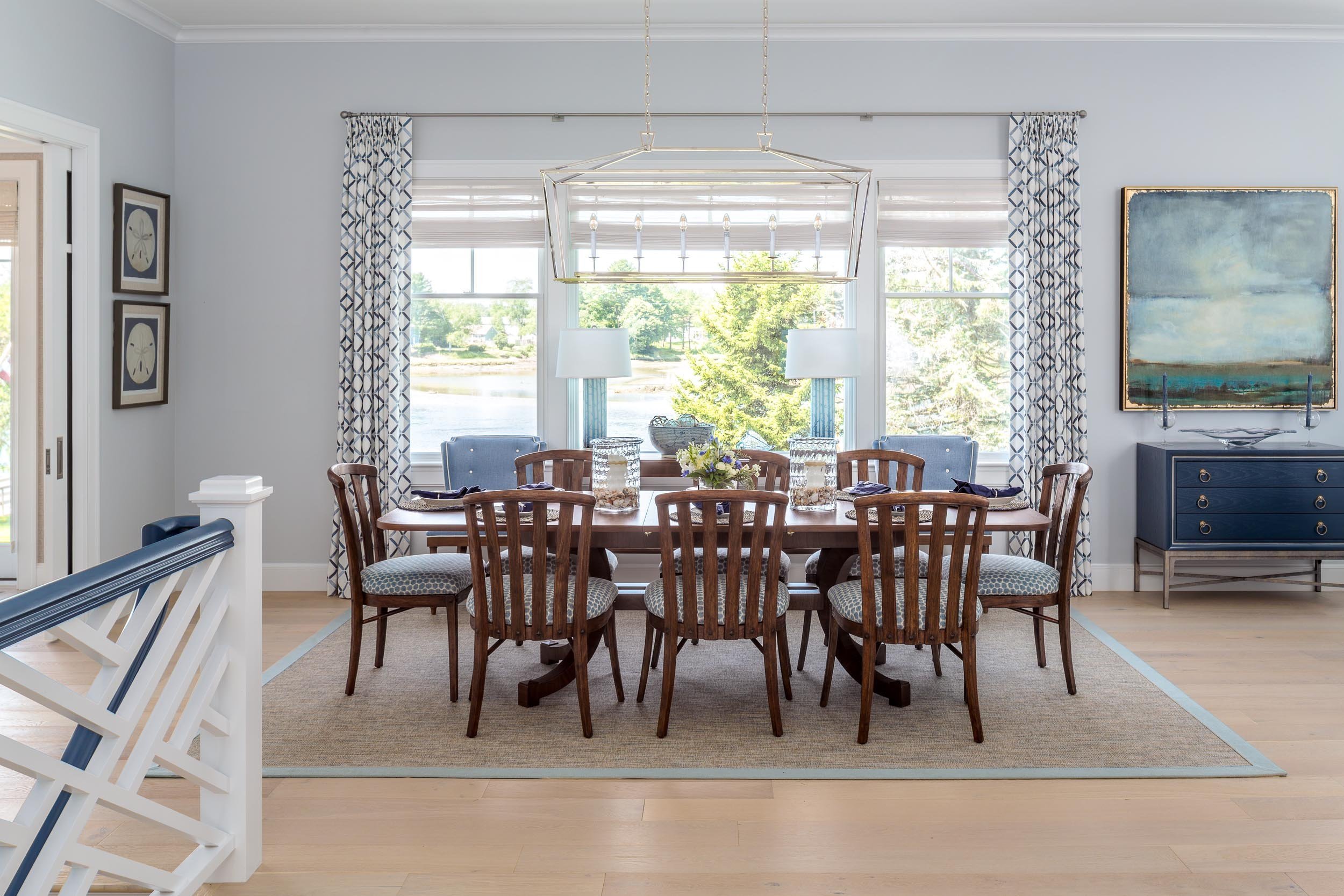 Dining room with a wooden table, eight chairs, a window view of trees and water, and blue and white decor.