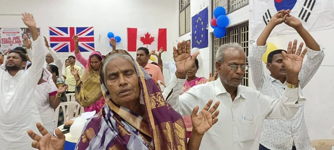 Men and women sing together, raising their hands in worship and prayer.