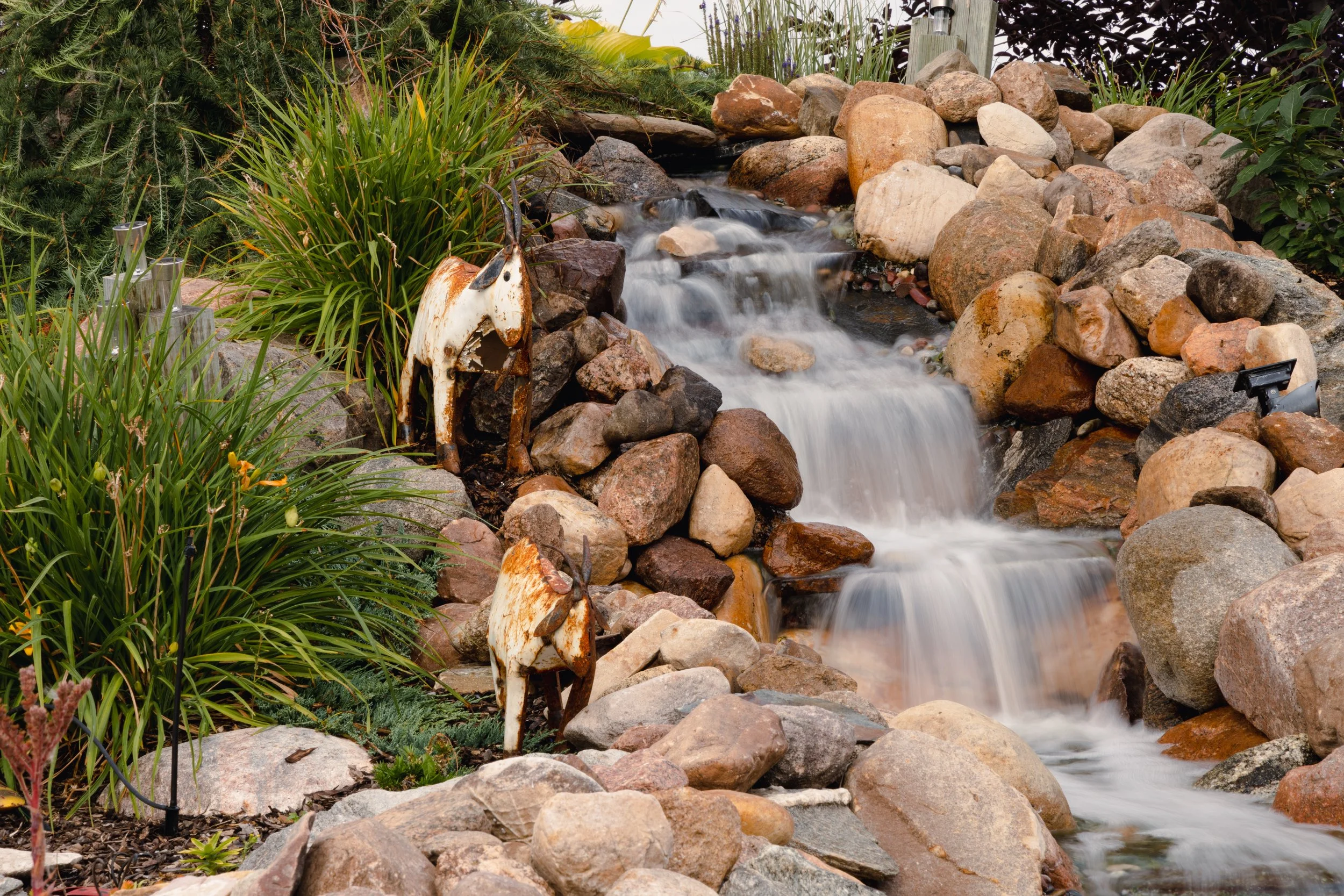 Flowing waterfall waterfeature stream surrounded by natural boulders and rock
