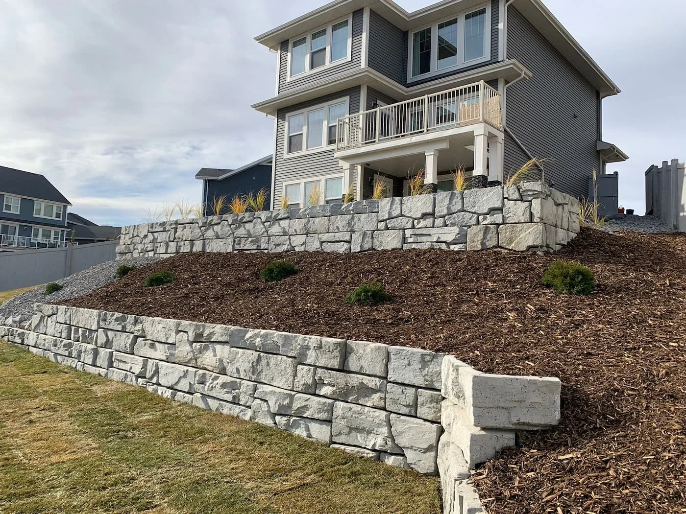 Large multileveled retaining wall in light grey with natural stone finish