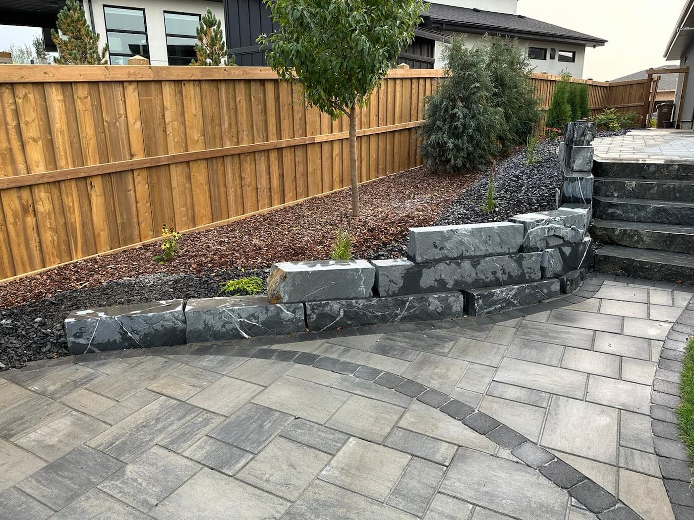 Ocean Pearl Natural stone retaining wall next to a paving stone patio