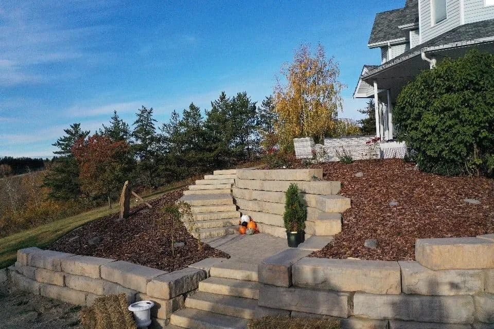 Large grande ledge wall in fon du lac with multiple stairs built on a hill to the front of a house