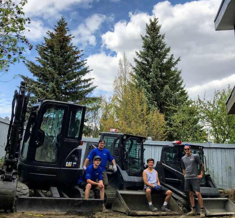 The team posing with our excavator and bobcat