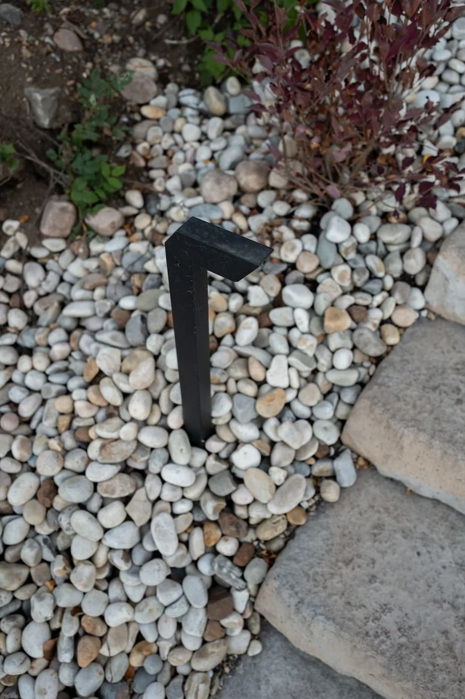 Black modern pathway light fixture and natural river rock
