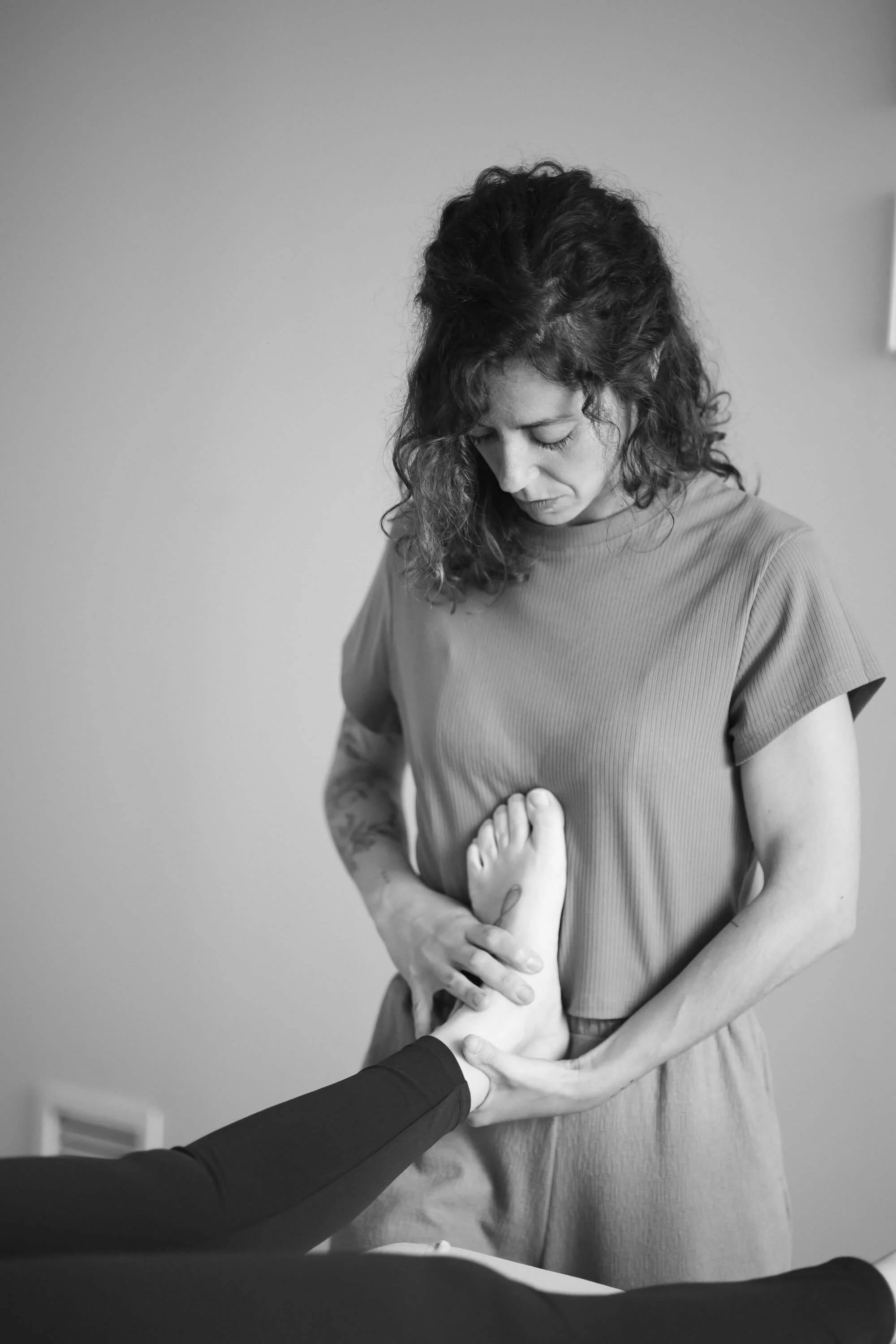 Alba sosteniendo un pie en sus manos en un entorno de consulta.