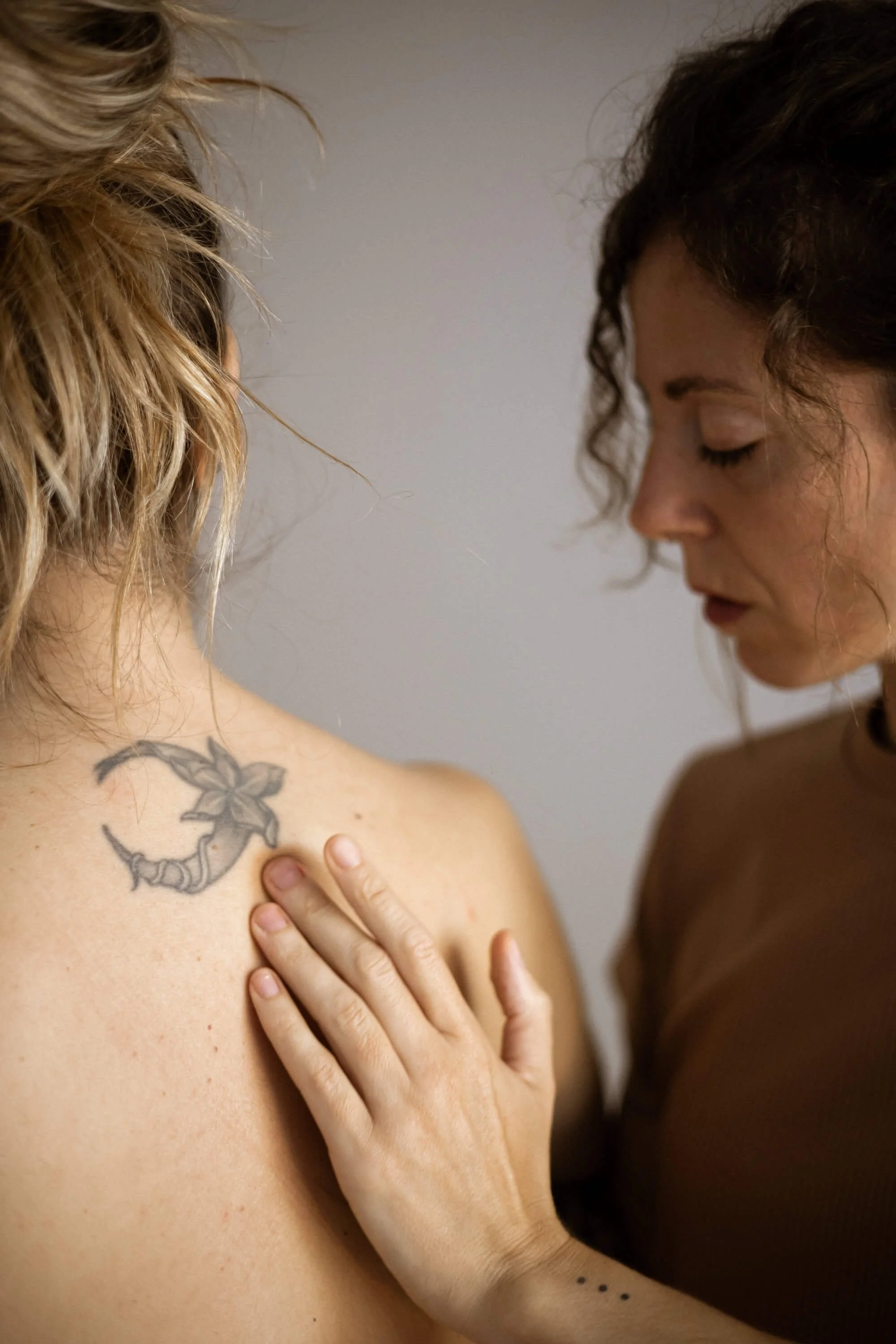 Primer plano de dos mujeres, una es Alba que toca la espalda de su consultante.