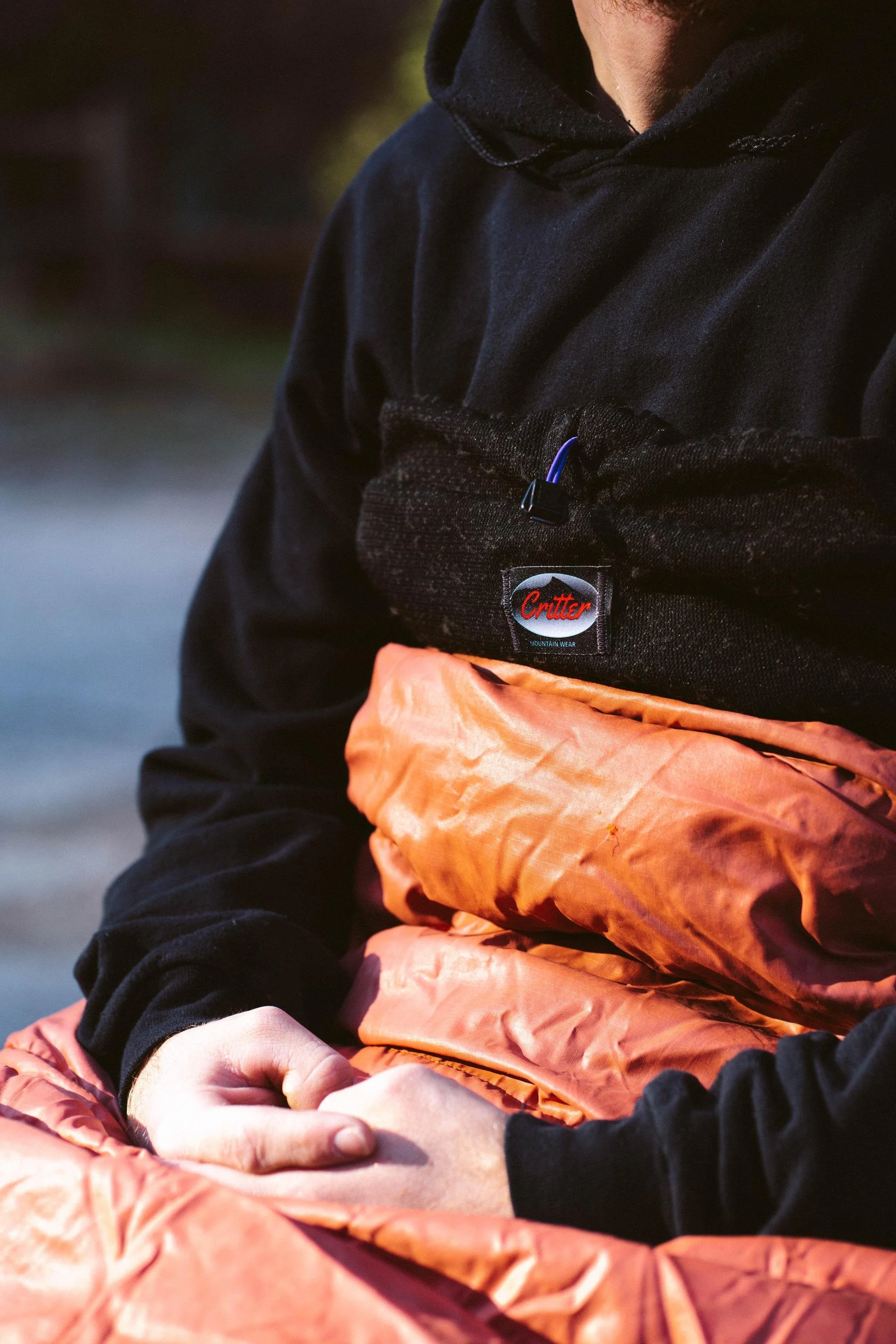 Someone sitting on the ground inside of the Potato Sack sleeping bag liner.