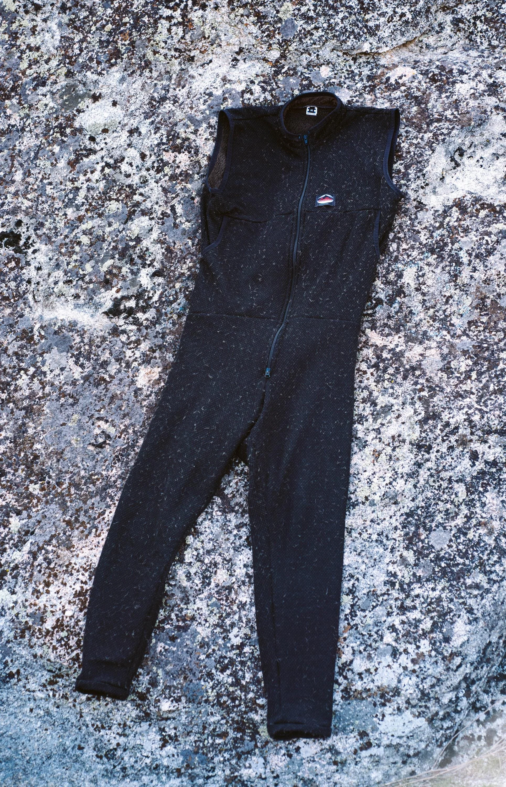 A Polartec Critter Birthday Suit laying flat on a rock showing the entire front with the arm holes, pockets and front zipper.