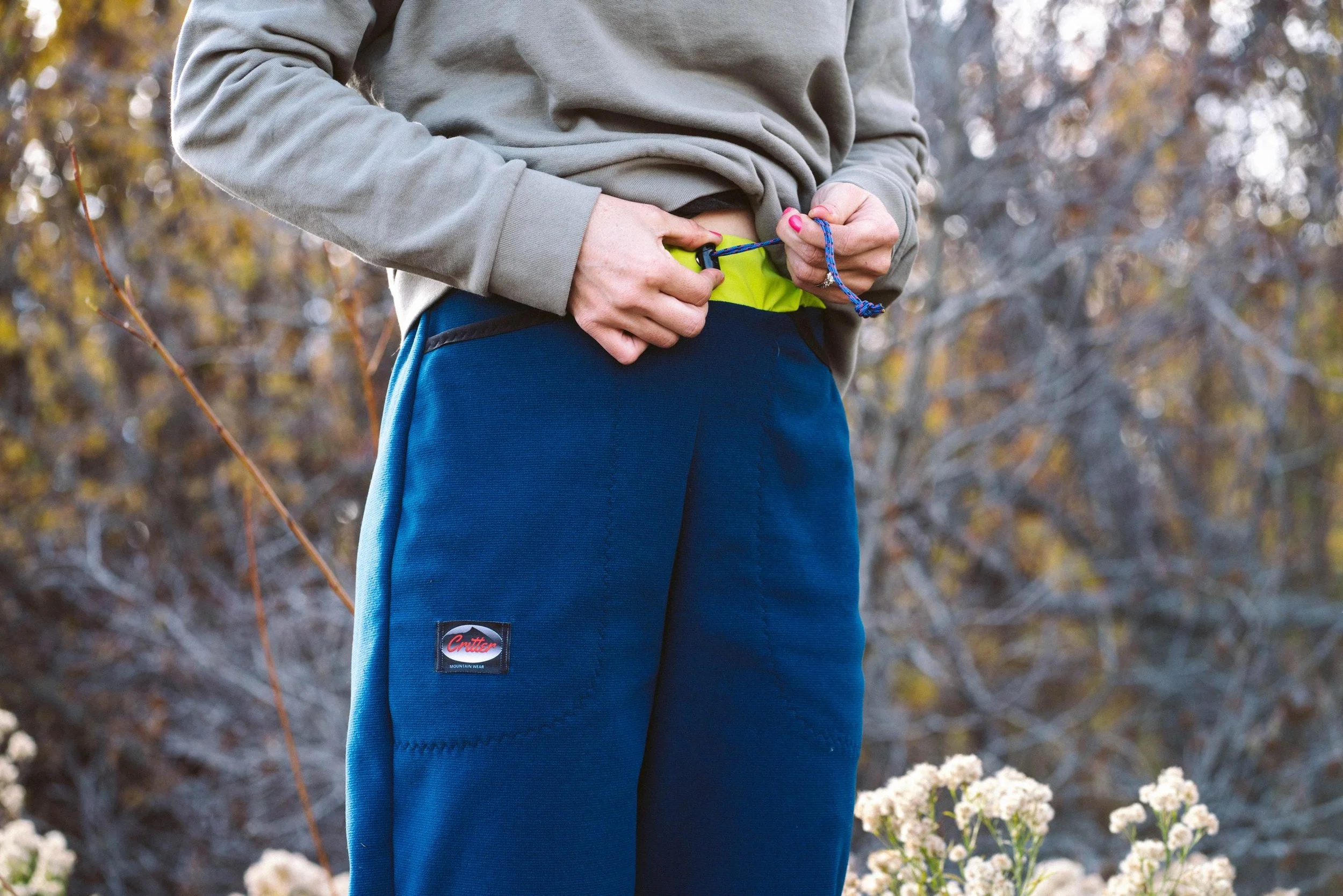 A person adjusting the drawcord on a pair of Polartec Critter Pants.