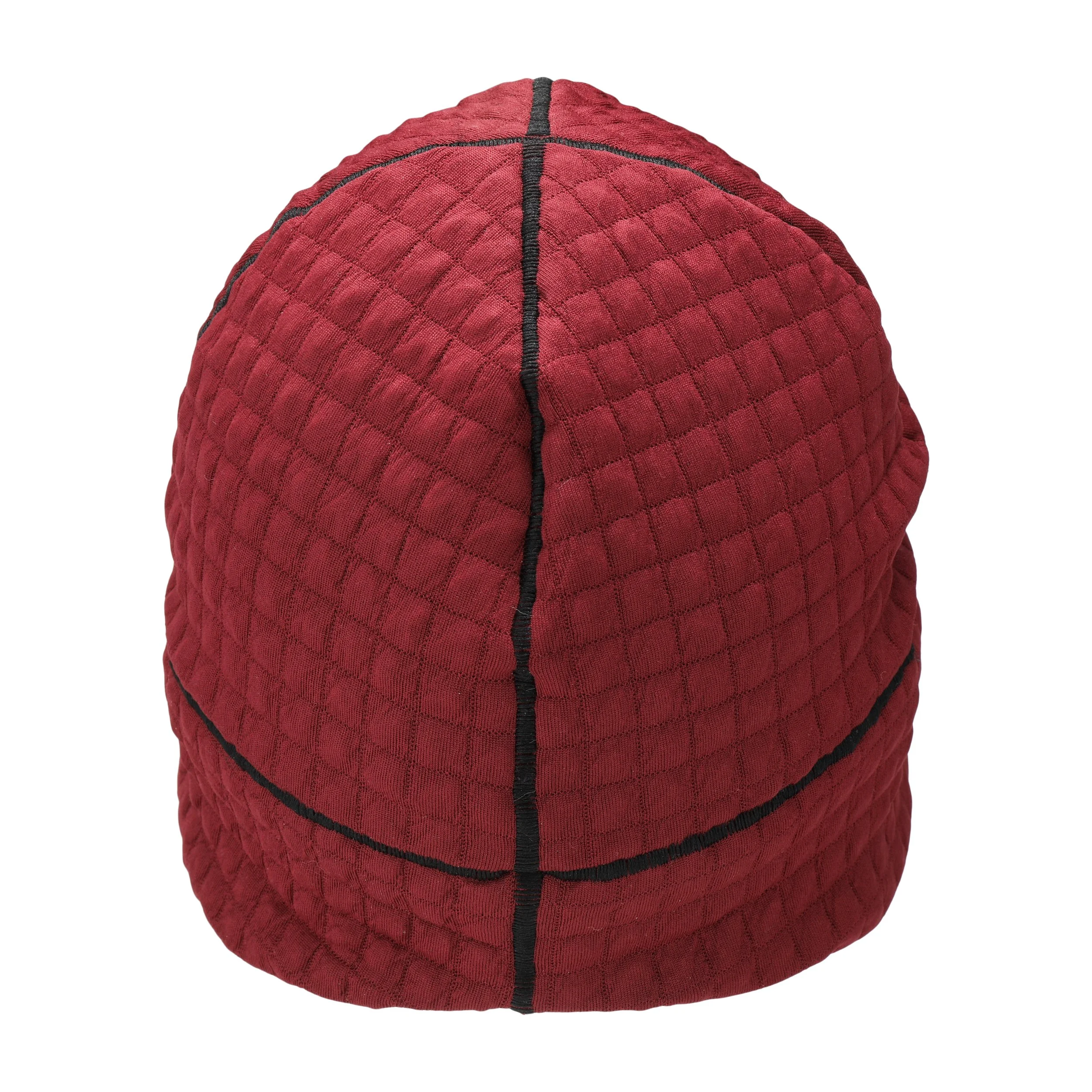 A red quilted beanie with a black seam down the center. The beanie is made of a soft, textured fabric and has a simple design.