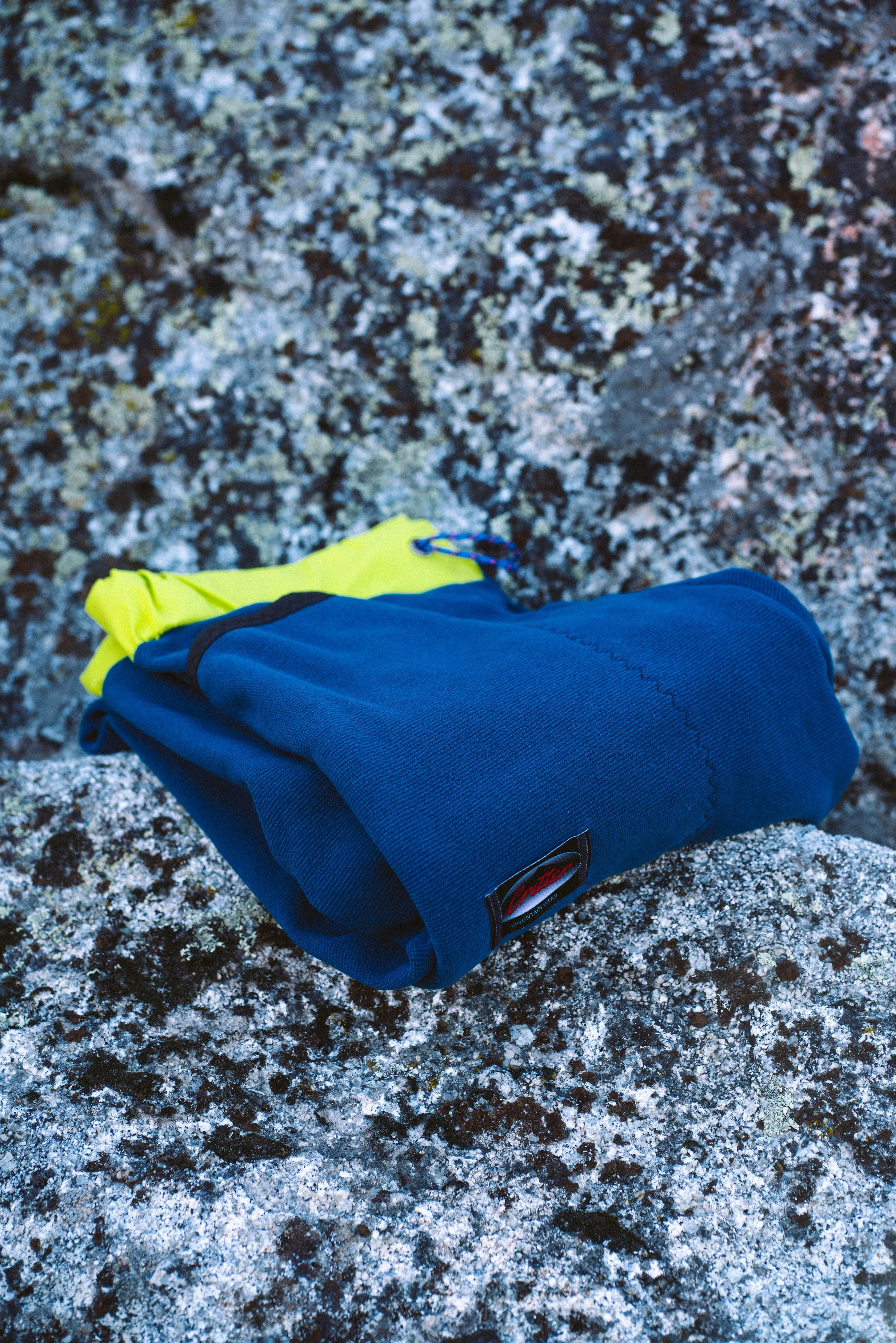 A pair of Polartec Critter Pants folded and lying on top of  a large rock.