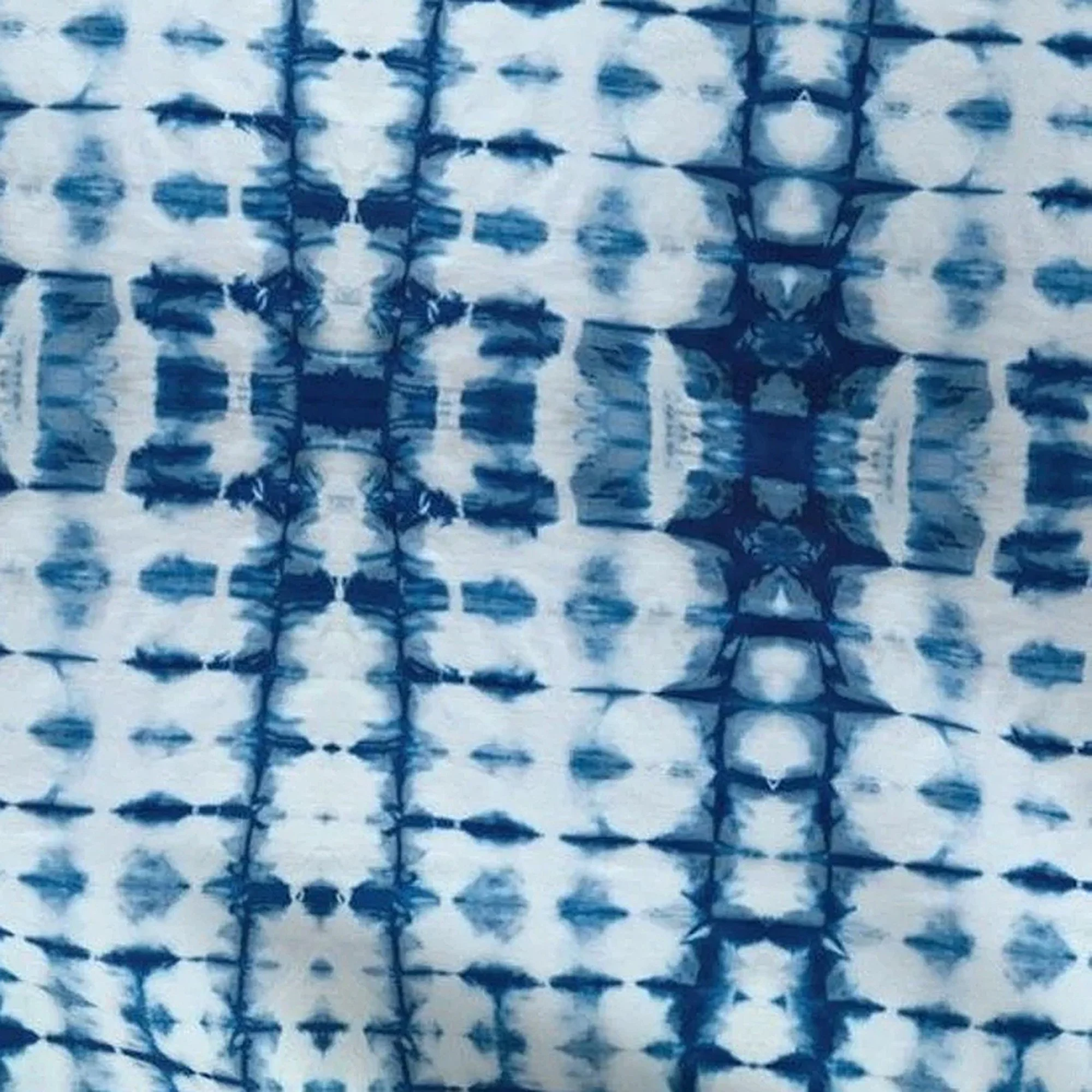 A recycled print fabric in white with a blue Shibori or tie-dye pattern.  The fabric is used on the front of the messenger bags.