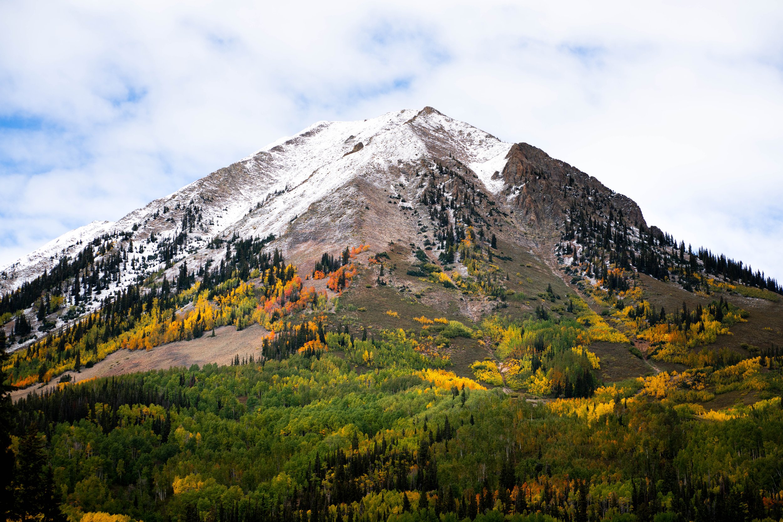 mountain with snow-capped peak and colorful autumn forest in foreground
