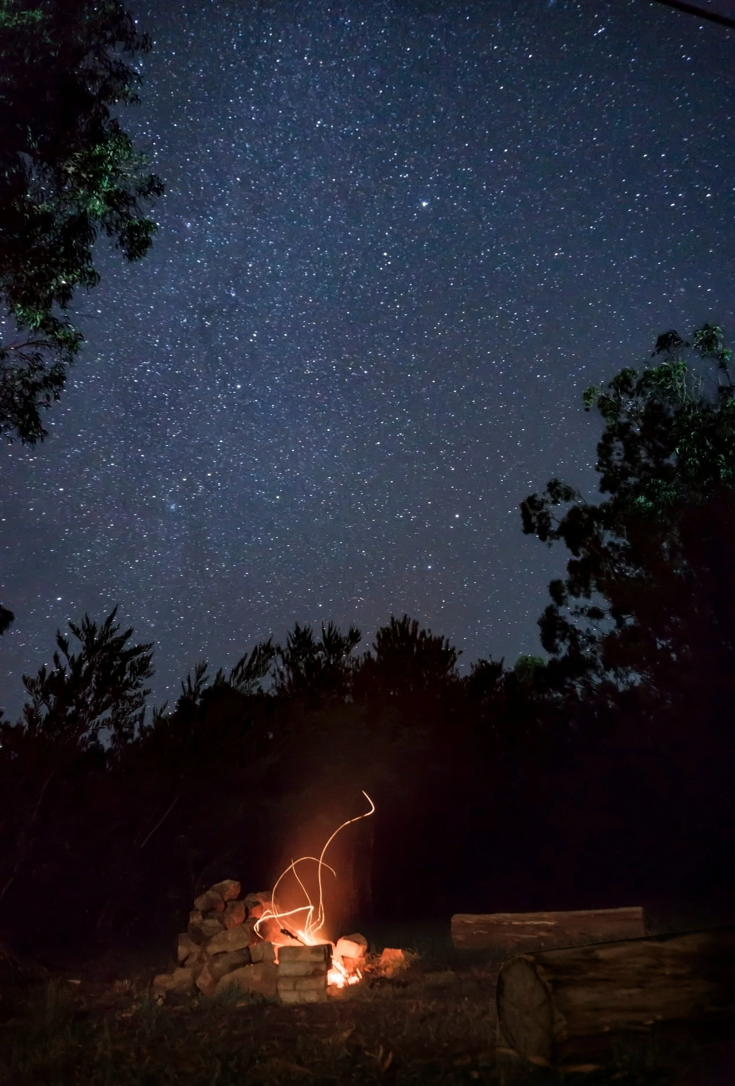 The night sky with stars and a campfire in the foreground.