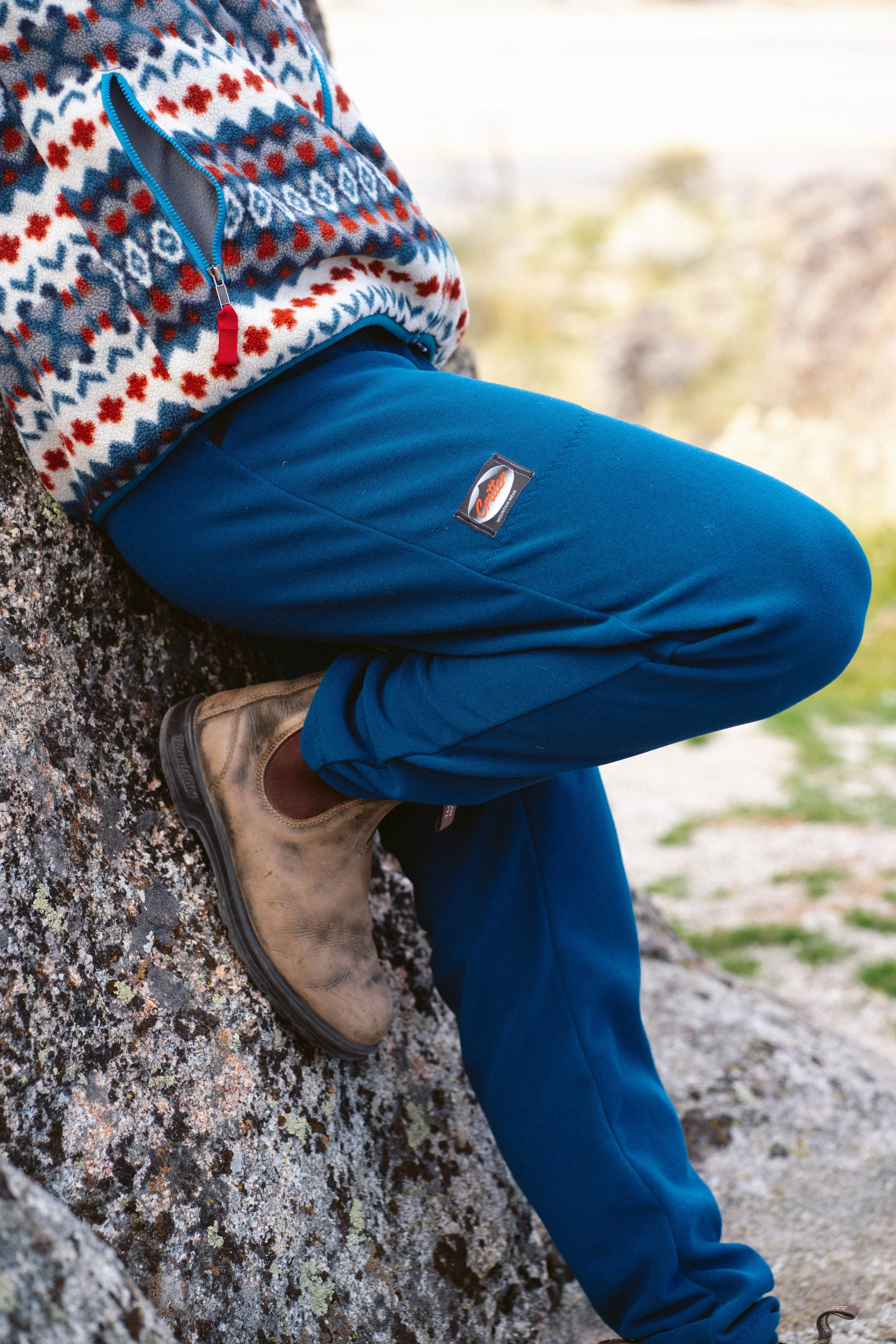 A person wearing a pair of Critter pants while leaning against a rock.