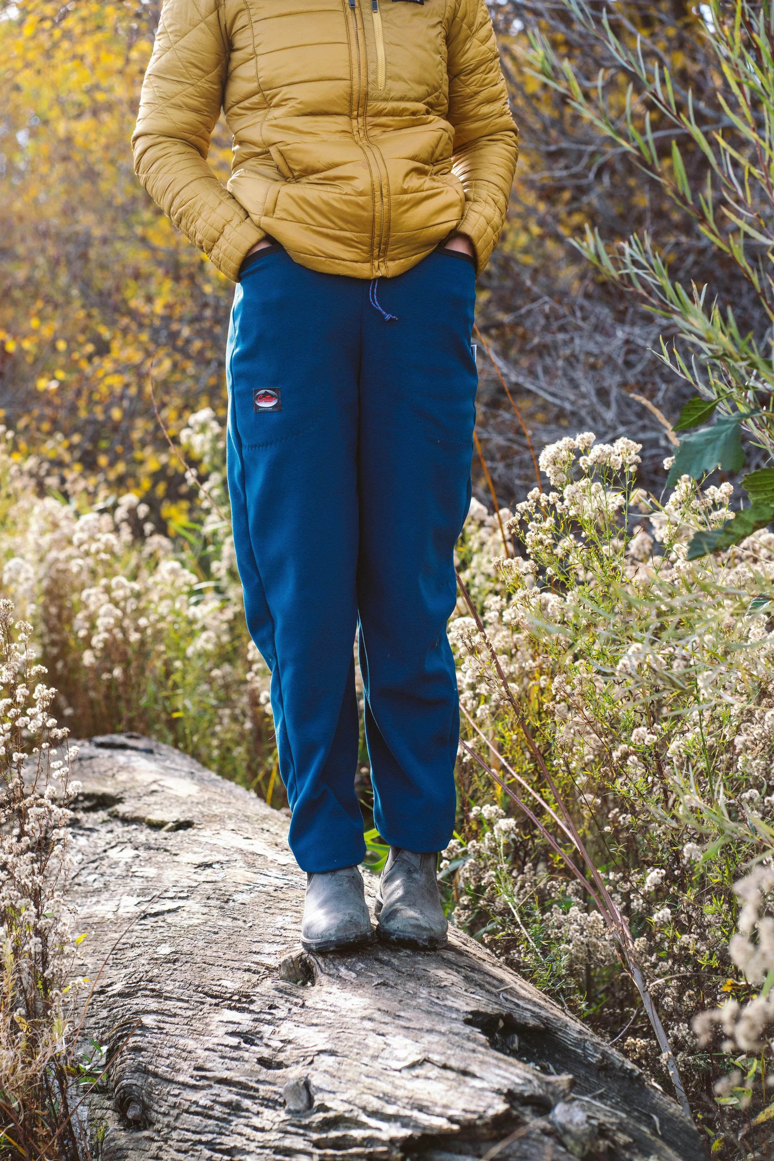 A person wearing a pair of Critter pants with their hands in the pockets.
