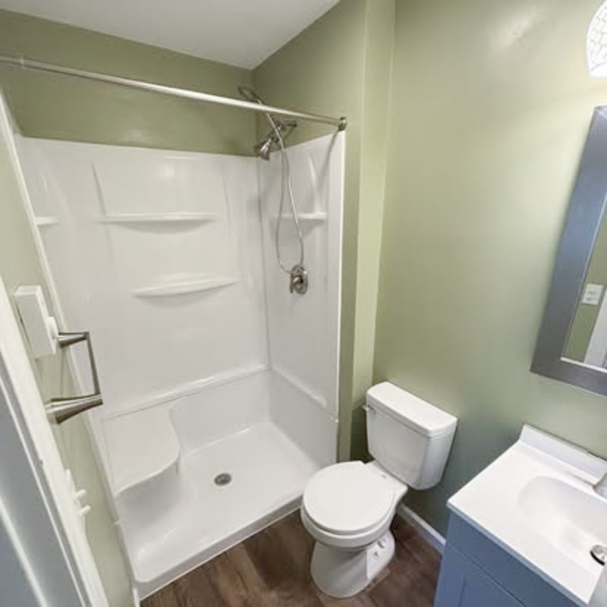 Small bathroom with a shower stall, toilet, and sink with a mirror.