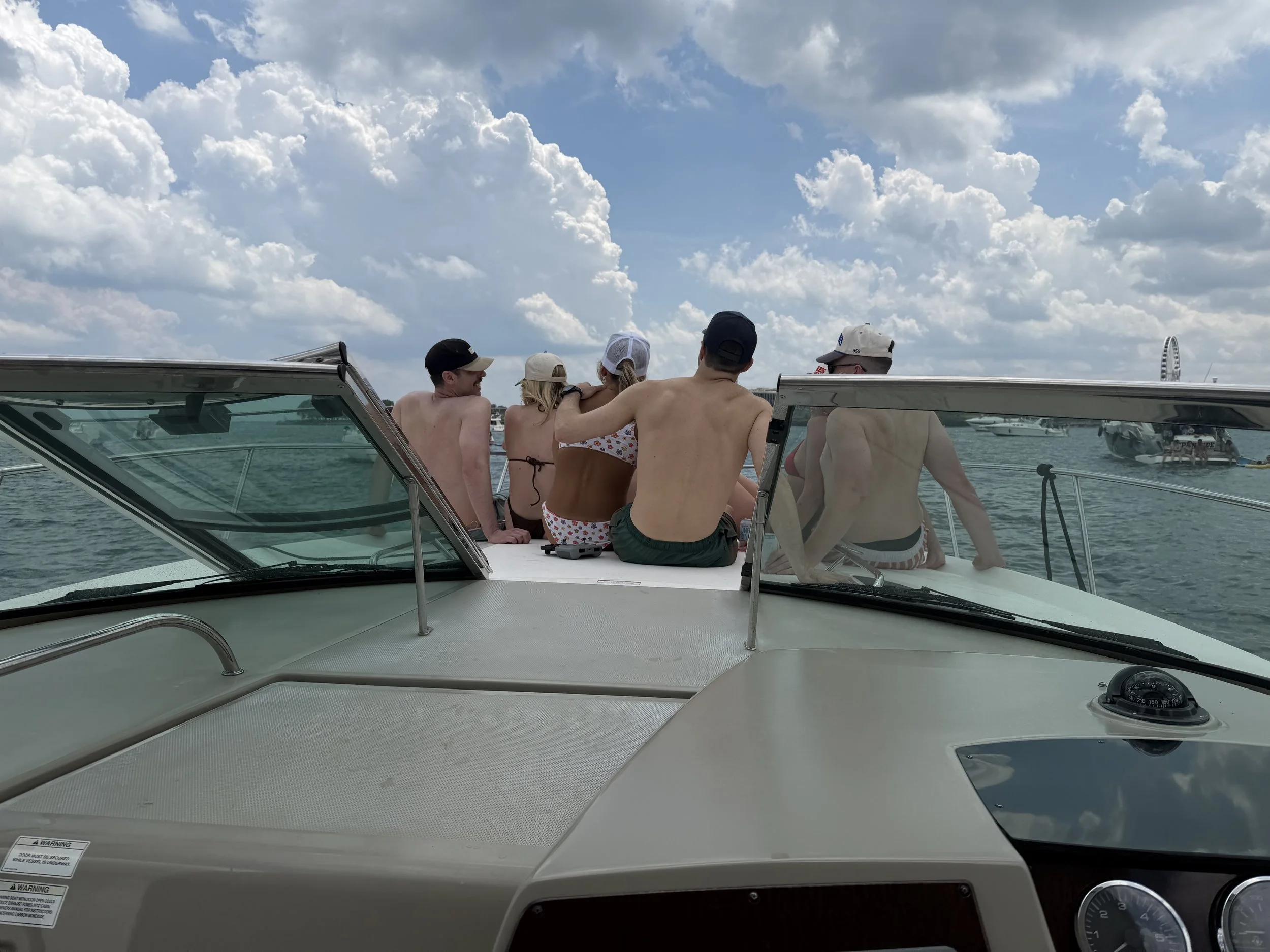 Group of people sitting on a boat enjoying a day on the water under a partly cloudy sky.