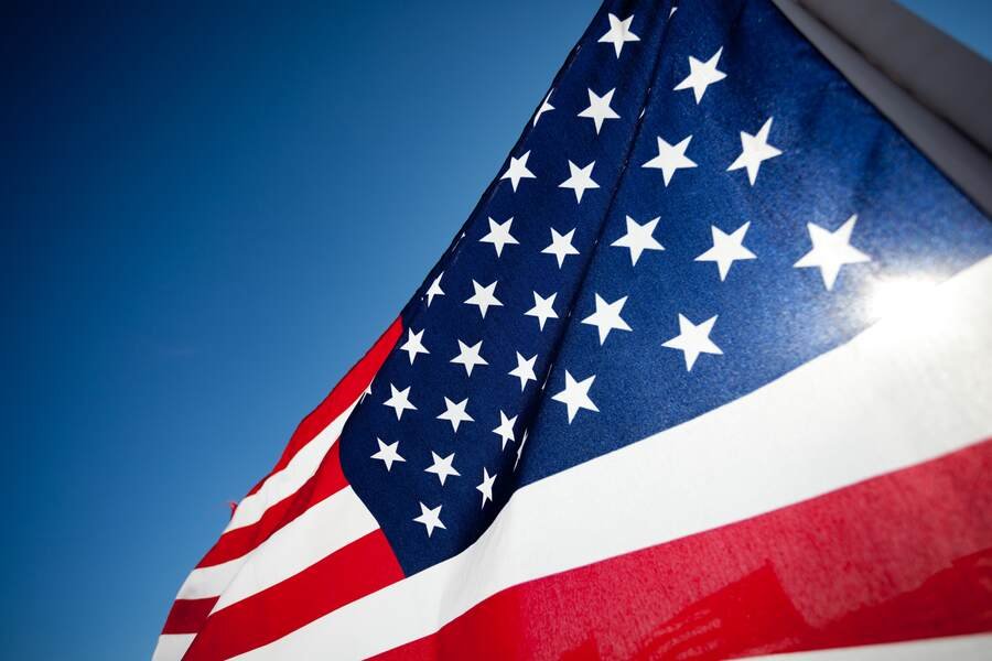 Close-up of the American flag waving against a clear blue sky.