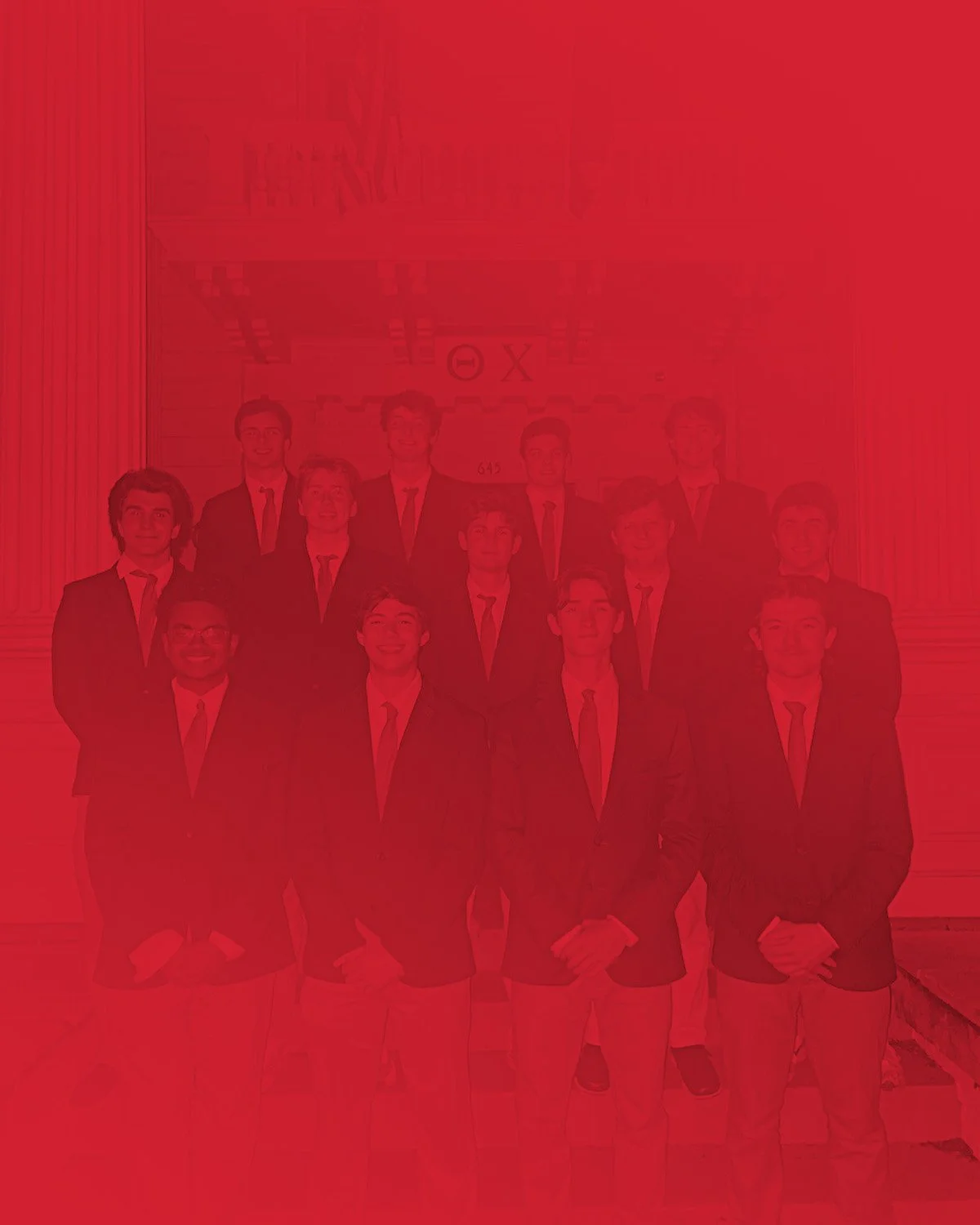 Group of young men in suits standing in front of a building with columns and an archway.