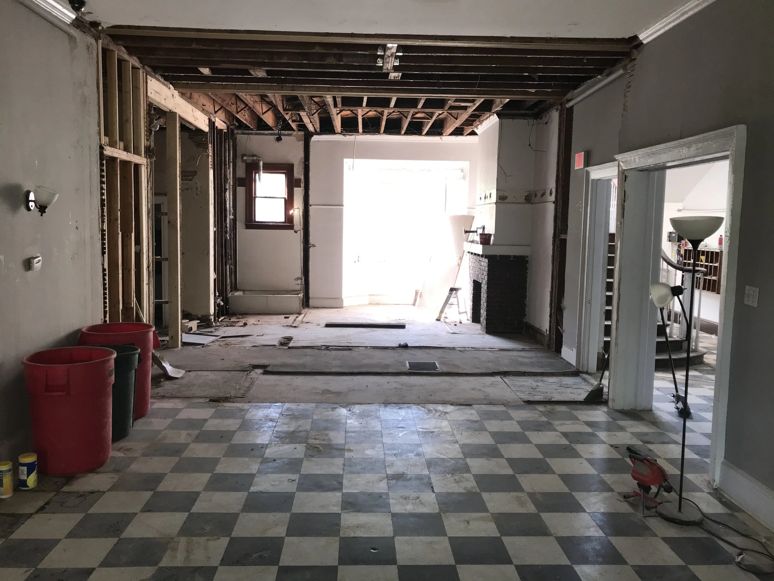 Interior of a house under renovation with part of the ceiling removed, exposing wooden beams, and construction equipment on the floor.