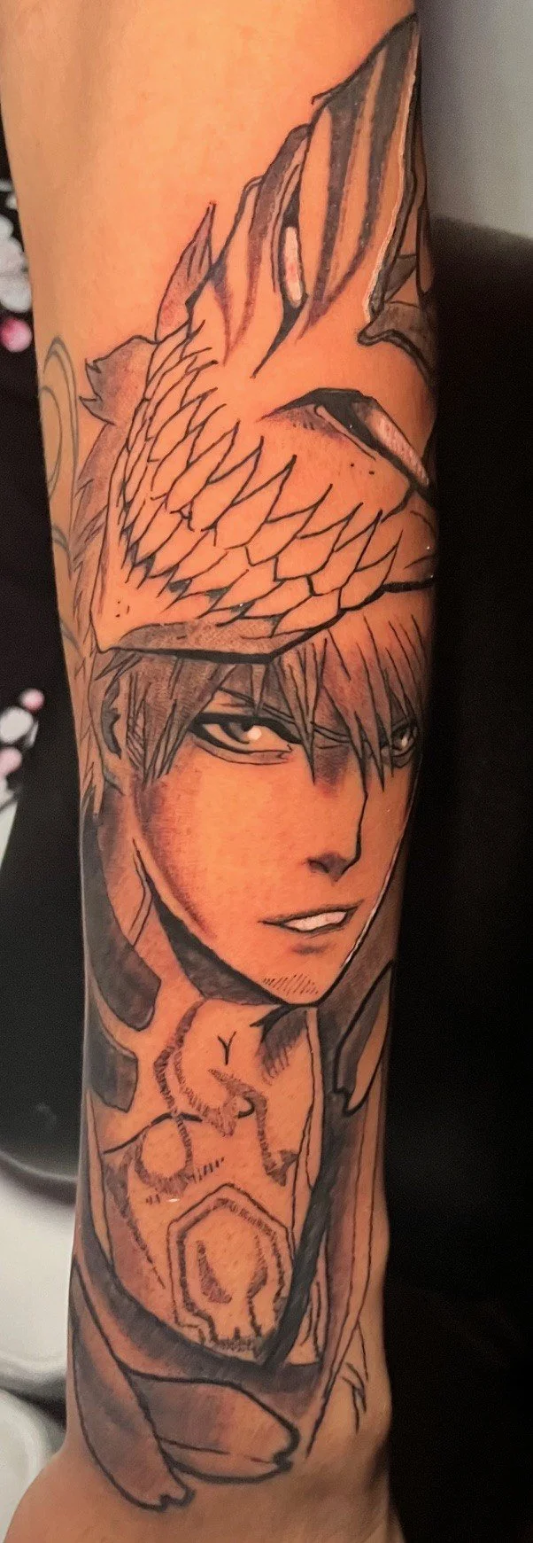 Tattoo of a dragon's head, a young man's face, and a skull on a person's arm.