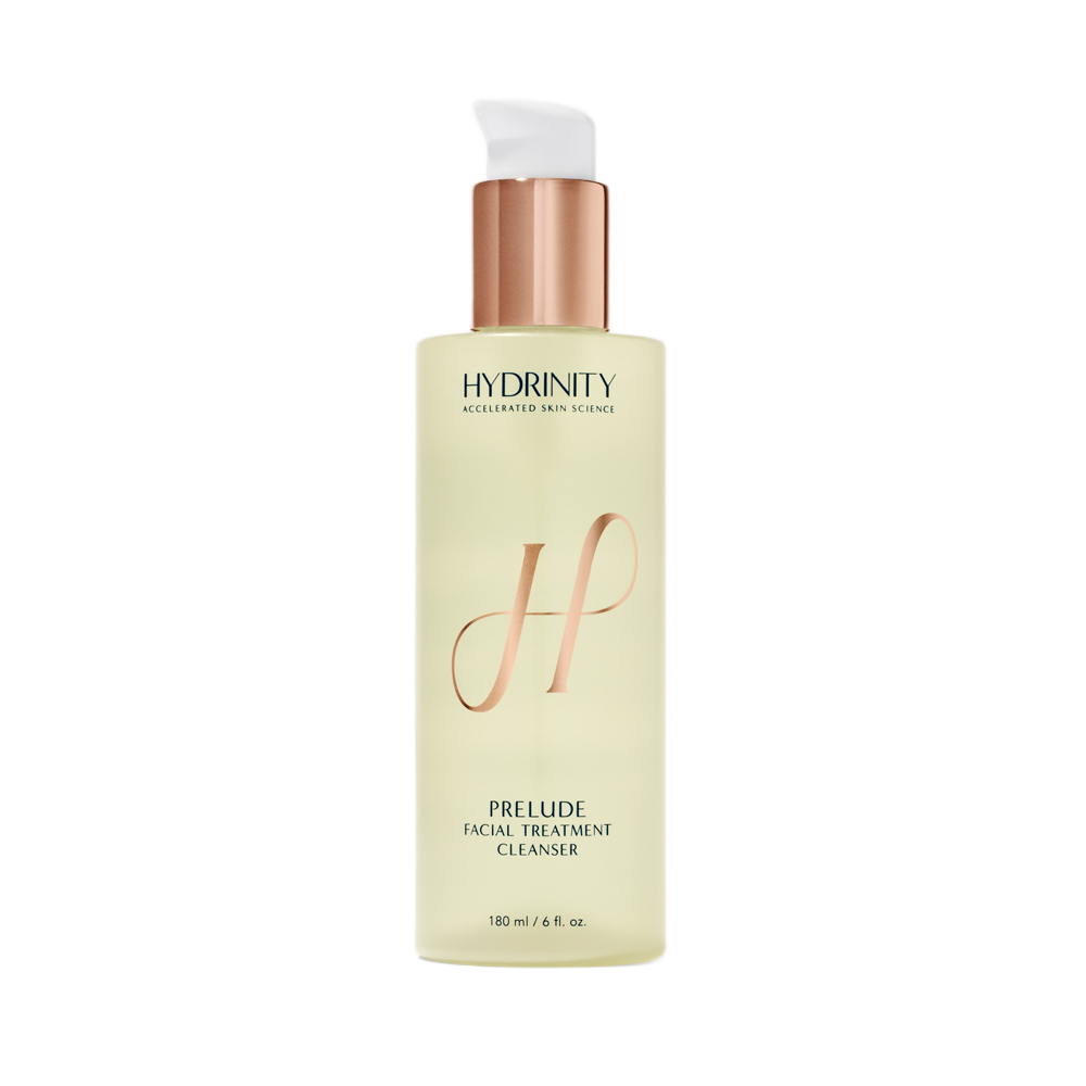 A bottle of Hydrinity Prelude facial treatment cleanser with a white pump dispenser and a gold-colored cap, featuring a large pink 'H' on the label.