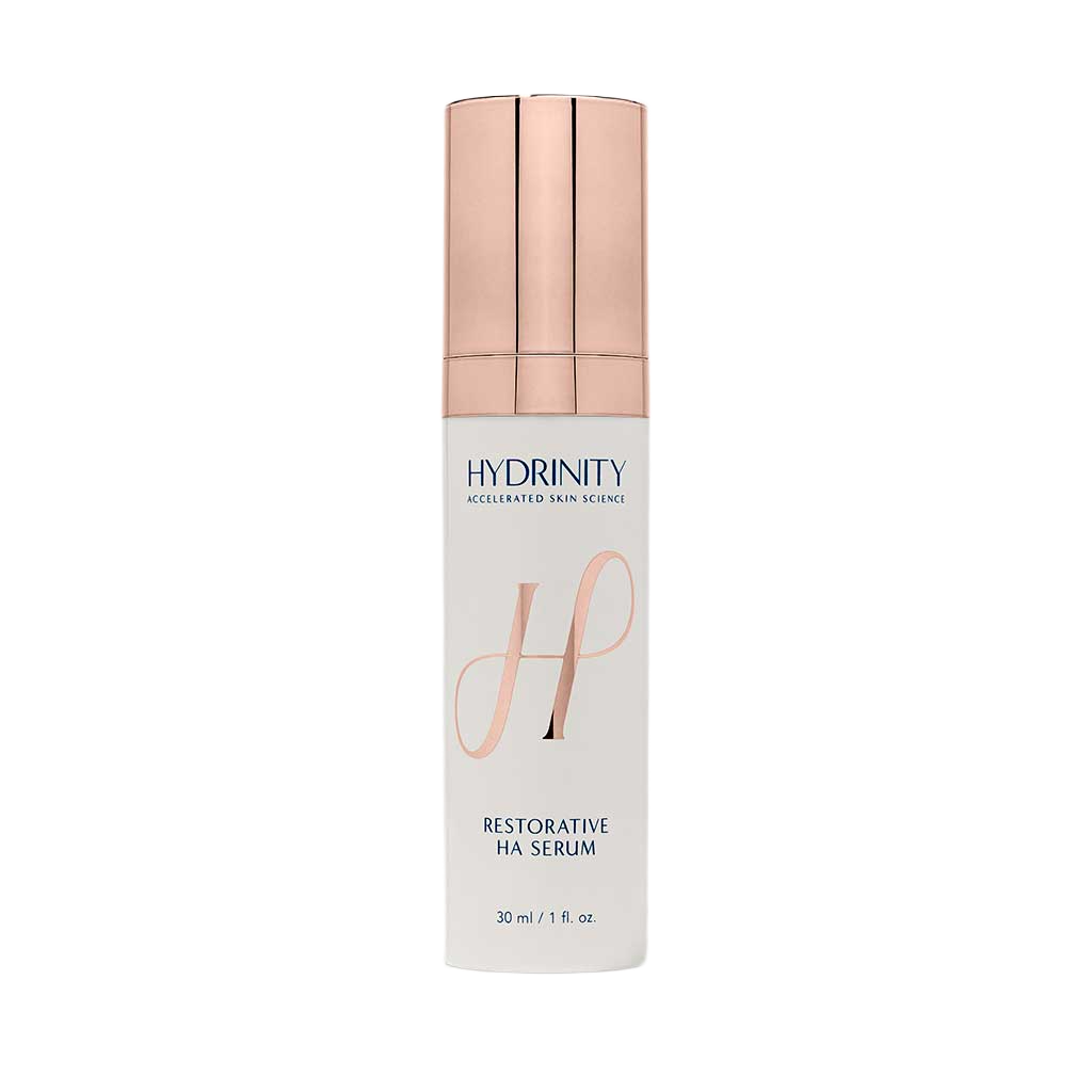 A white bottle of Hydrinity Restorative HA Serum with a rose gold cap and a pink stylized 'H' on the front.