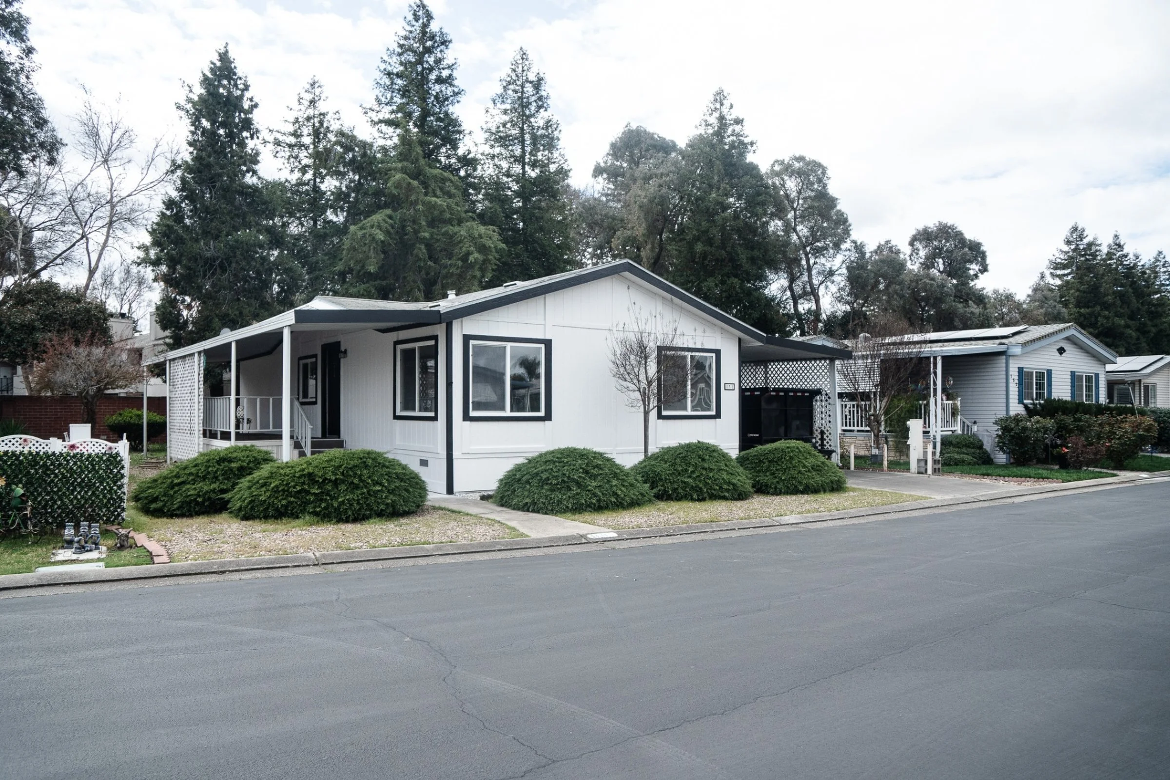 A mountain landscape with snow-capped peaks, rolling hills, and a small building with a stone wall in the foreground.