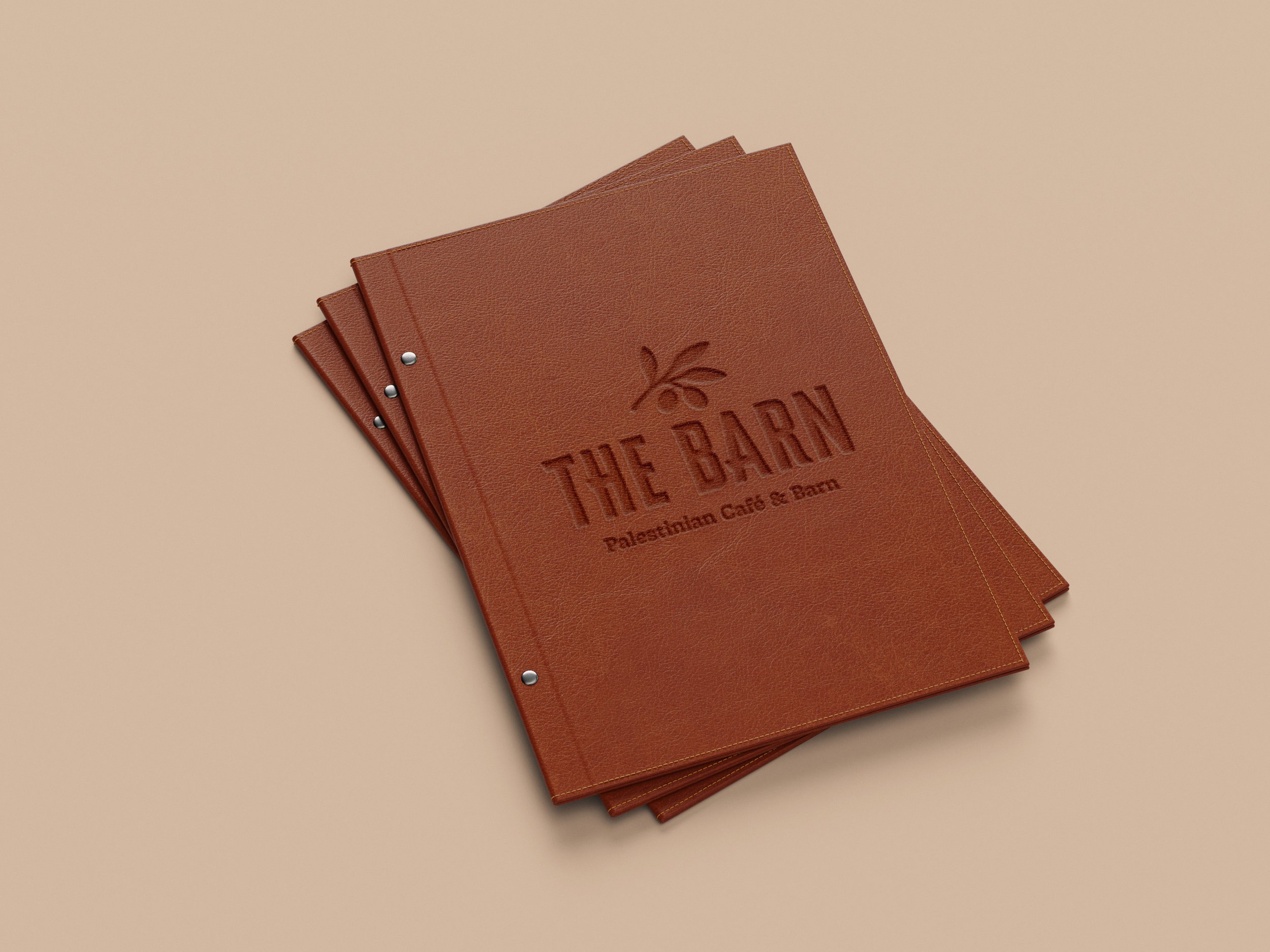 Three brown menus with embossed text reading "The Barn Palestinian Cafe & Barn" on a beige background.