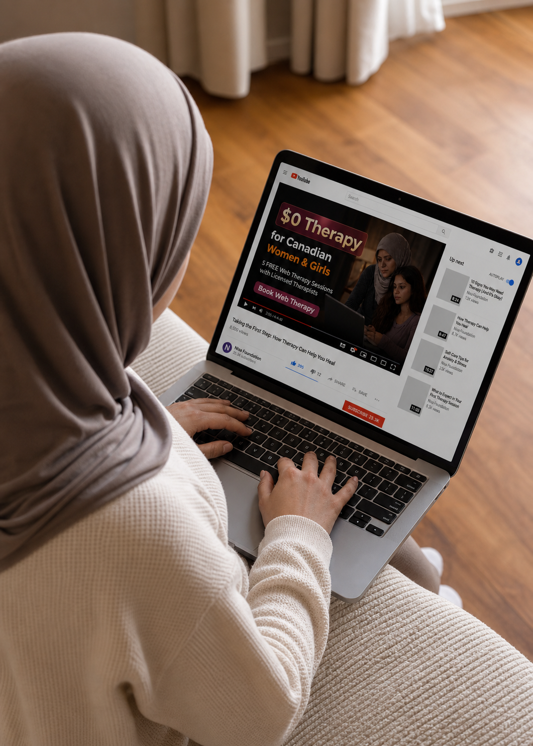 A woman wearing a beige hijab and sweater watching a YouTube video on her laptop about free therapy sessions for Canadian women and girls.