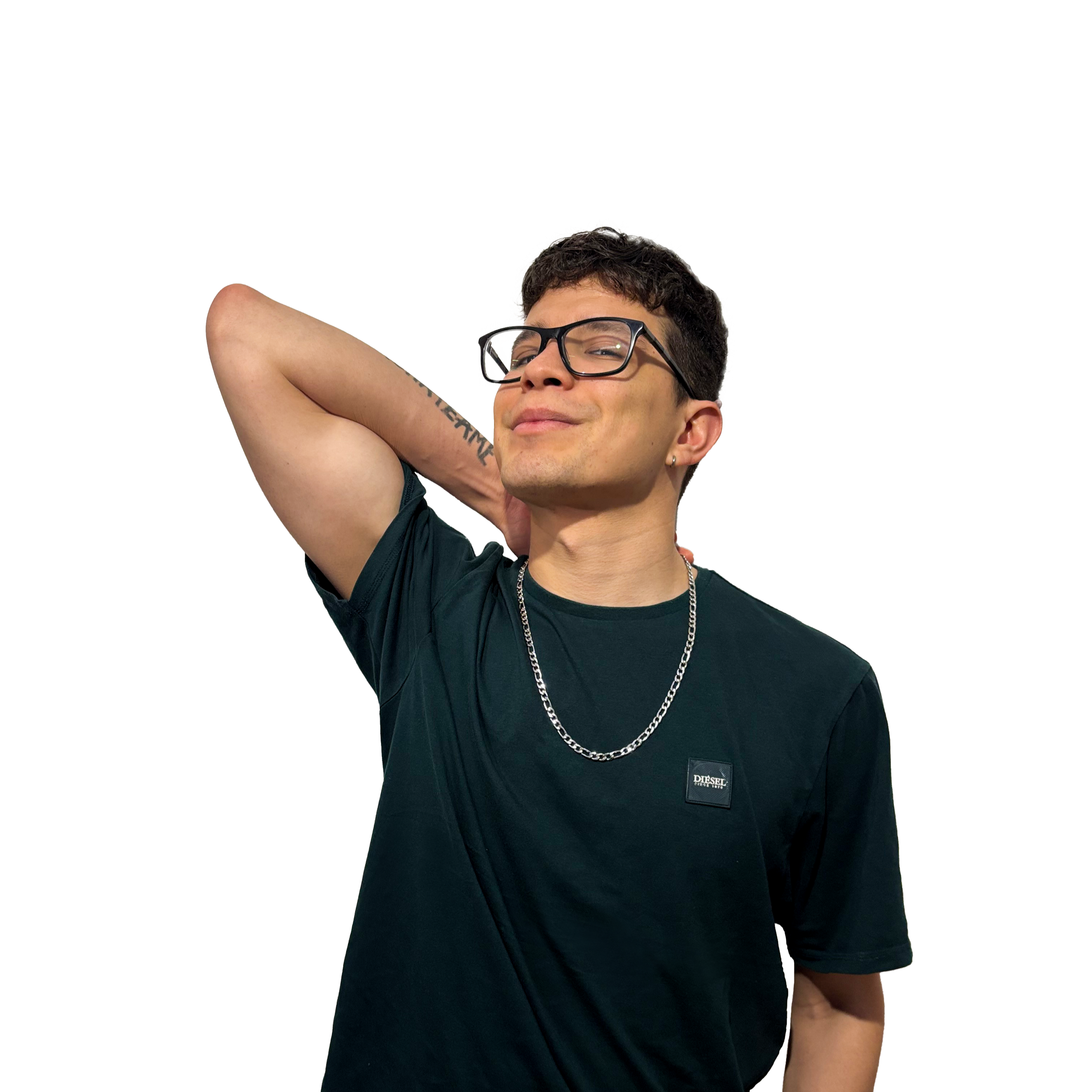 A young man with black hair, glasses, and tattoos, wearing a black shirt and silver chain necklace, is smiling with his eyes slightly squinted while resting his arm behind his head.