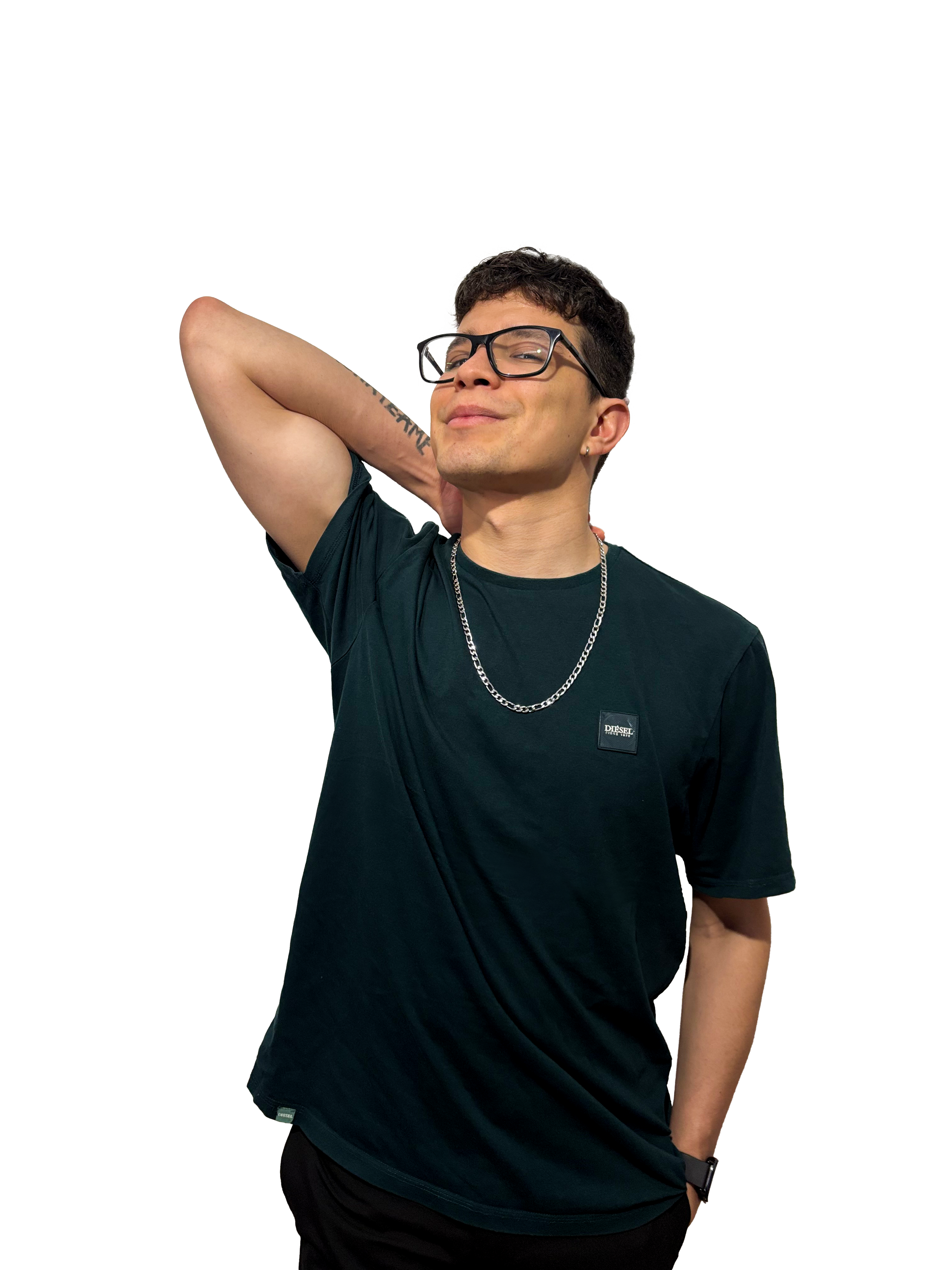 A young man with short dark hair, glasses, and a slight smile, wearing a black t-shirt with a Diesel logo, a silver chain necklace, and a black wristwatch, standing with one hand behind his head against a plain background.